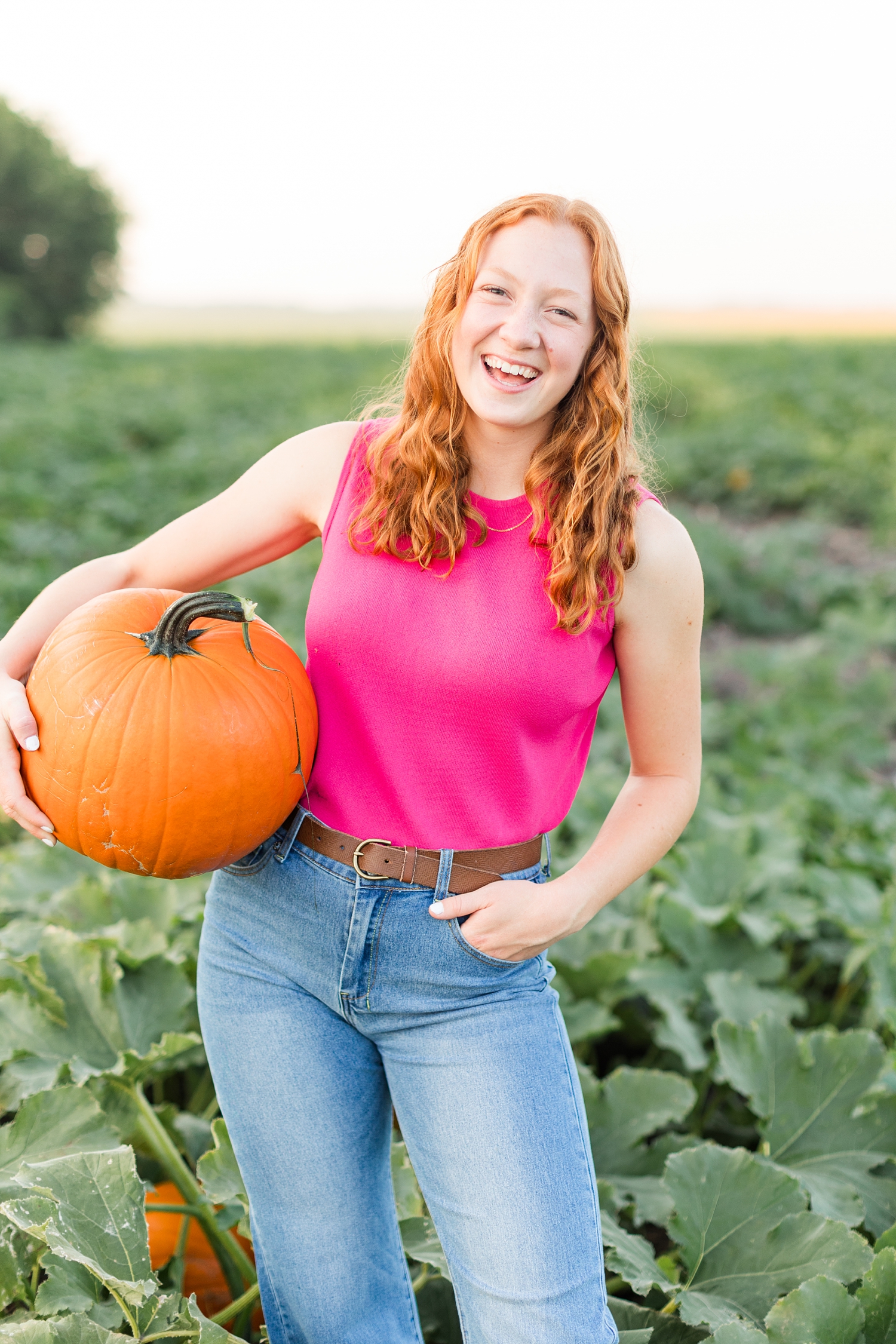 Violet laughs while she holds a pumpkin in her family's pumpkin patch at Bode Moonlight Gardens | CB Studio