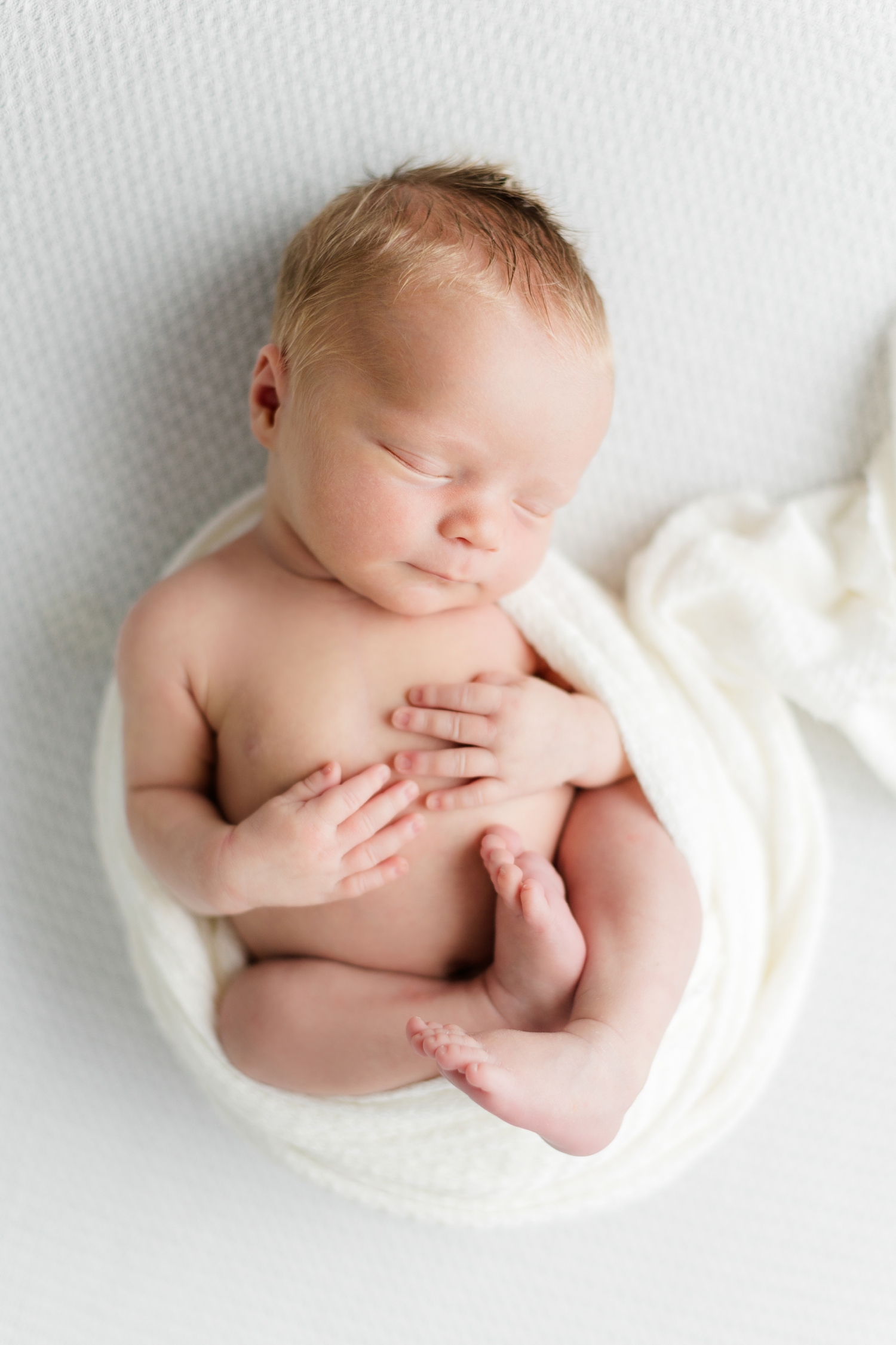 Baby Wyatt sleeps peacefully wrapped partially in a white swaddle | CB Studio