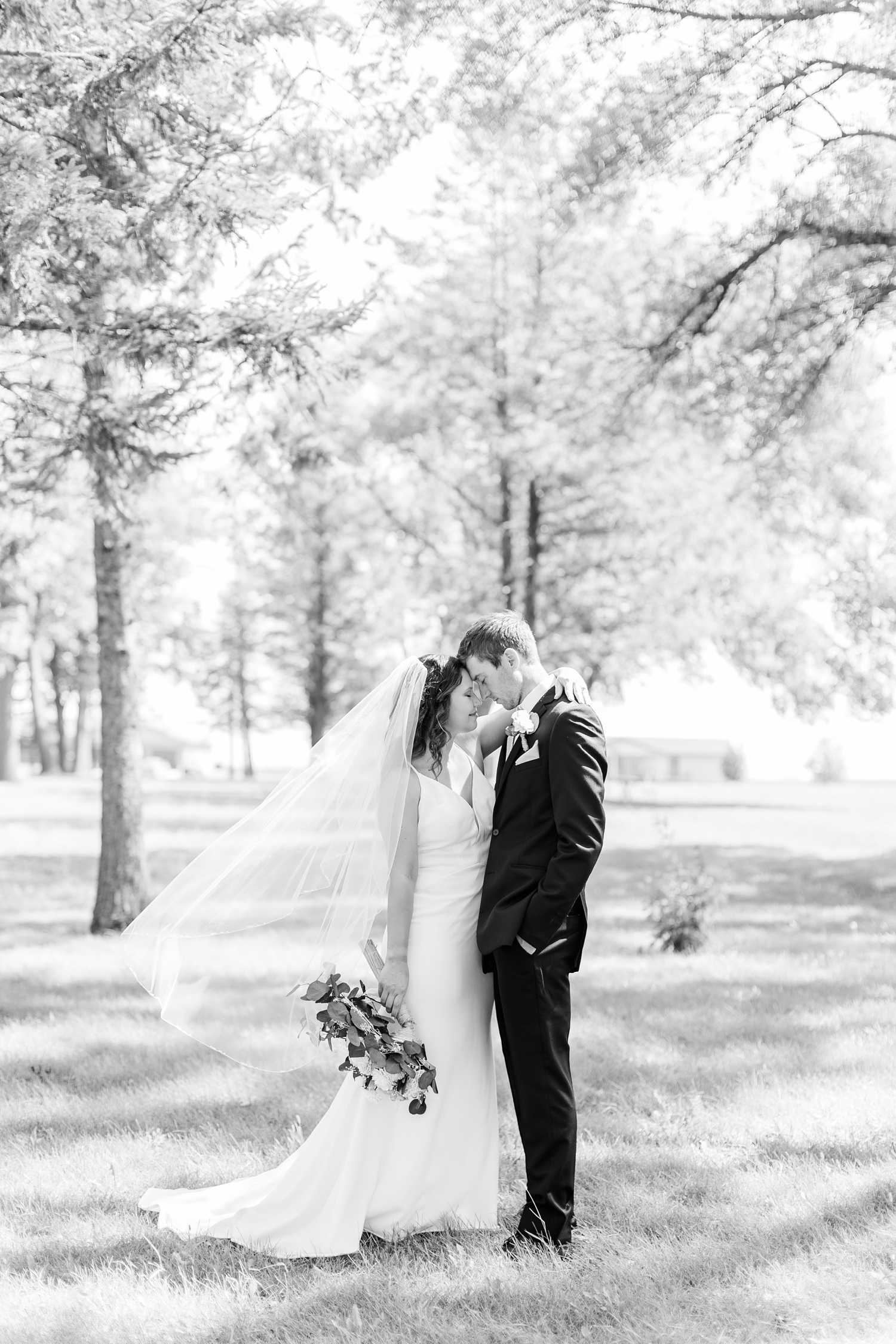 Grant and Alyssa rest their foreheads together as her veil flows in the wind at 5 Island Campground in Emmetsburg, IA | CB Studio