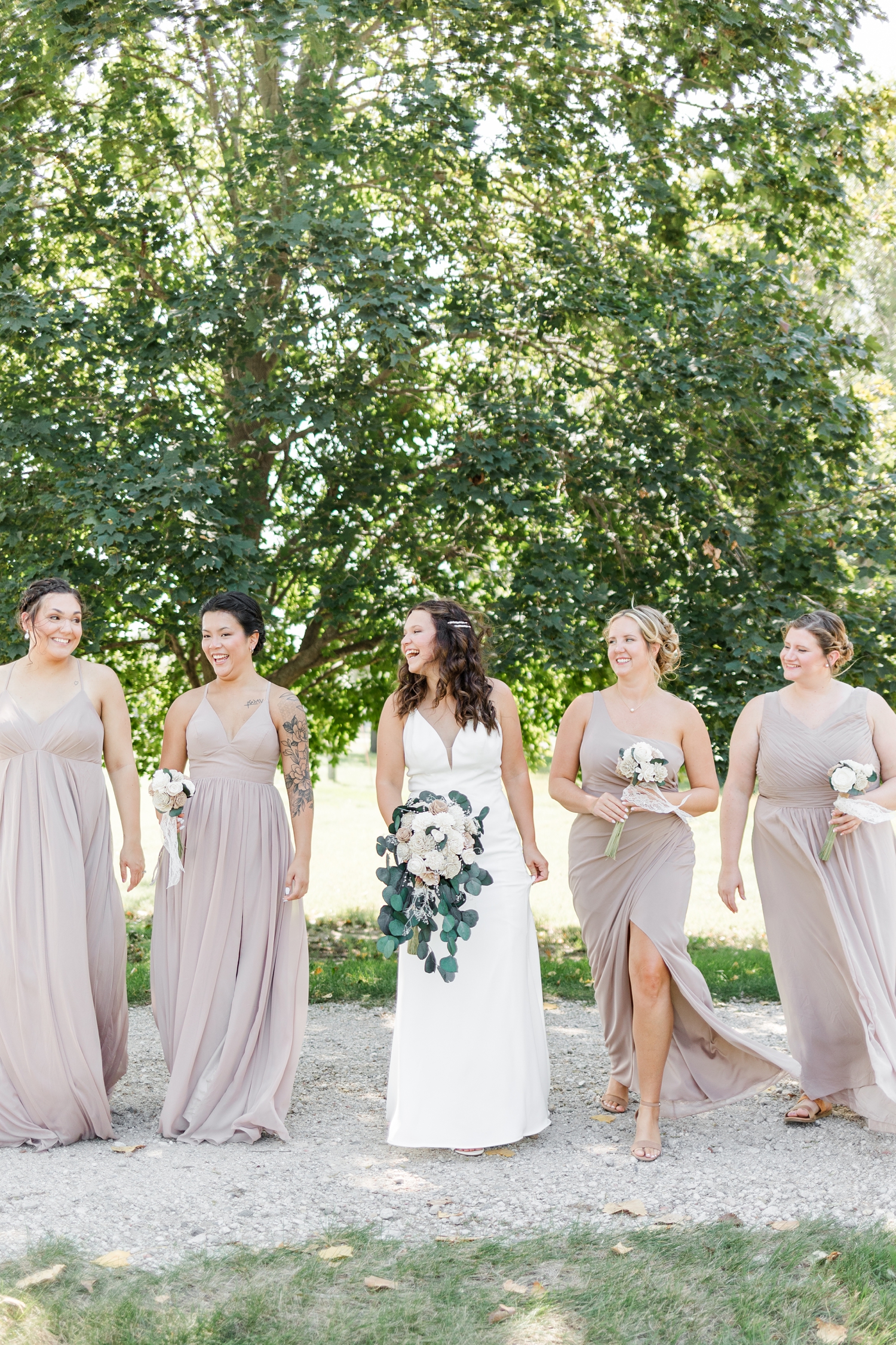 Alyssa and her bridesmaids walk together laughing at 5 Island Campground in Emmetsburg, IA | CB Studio