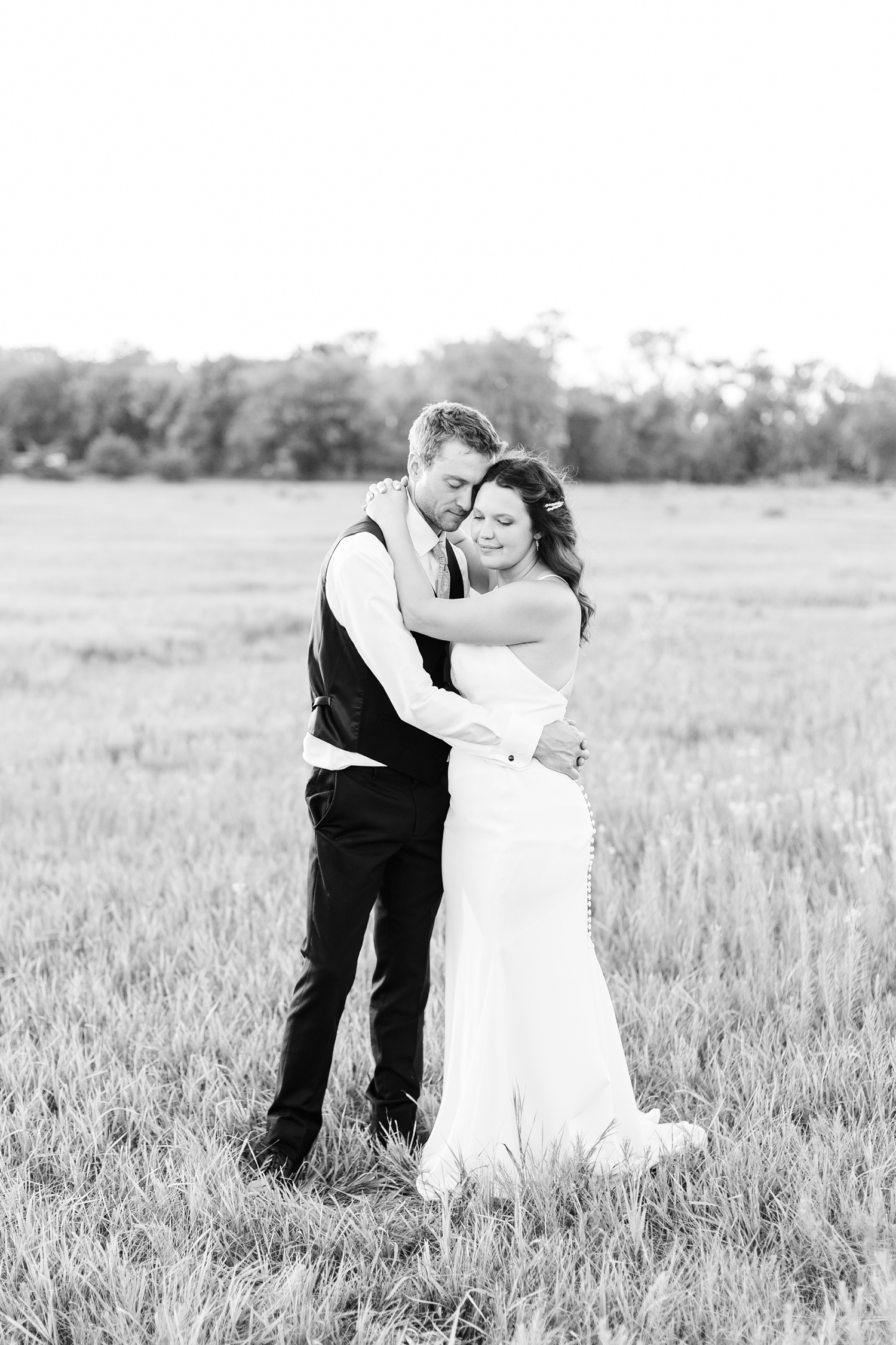 Alyssa and Grant embrace in a grassy pasture at sunset on their wedding day in Emmetsburg, IA | CB Studio