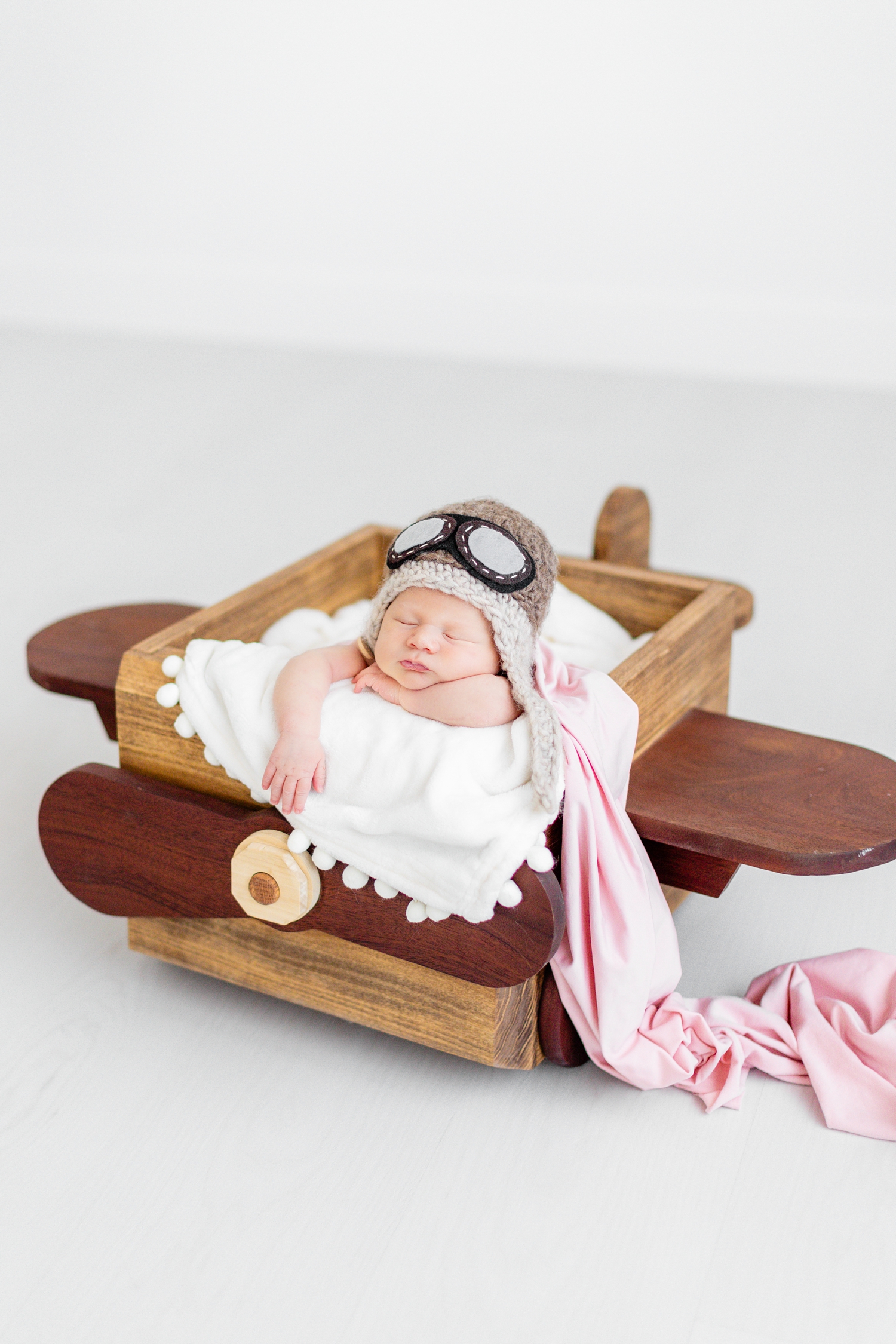 Newborn baby Jade sleeps "bucket pose" style in a wooden airplane box | CB Studio