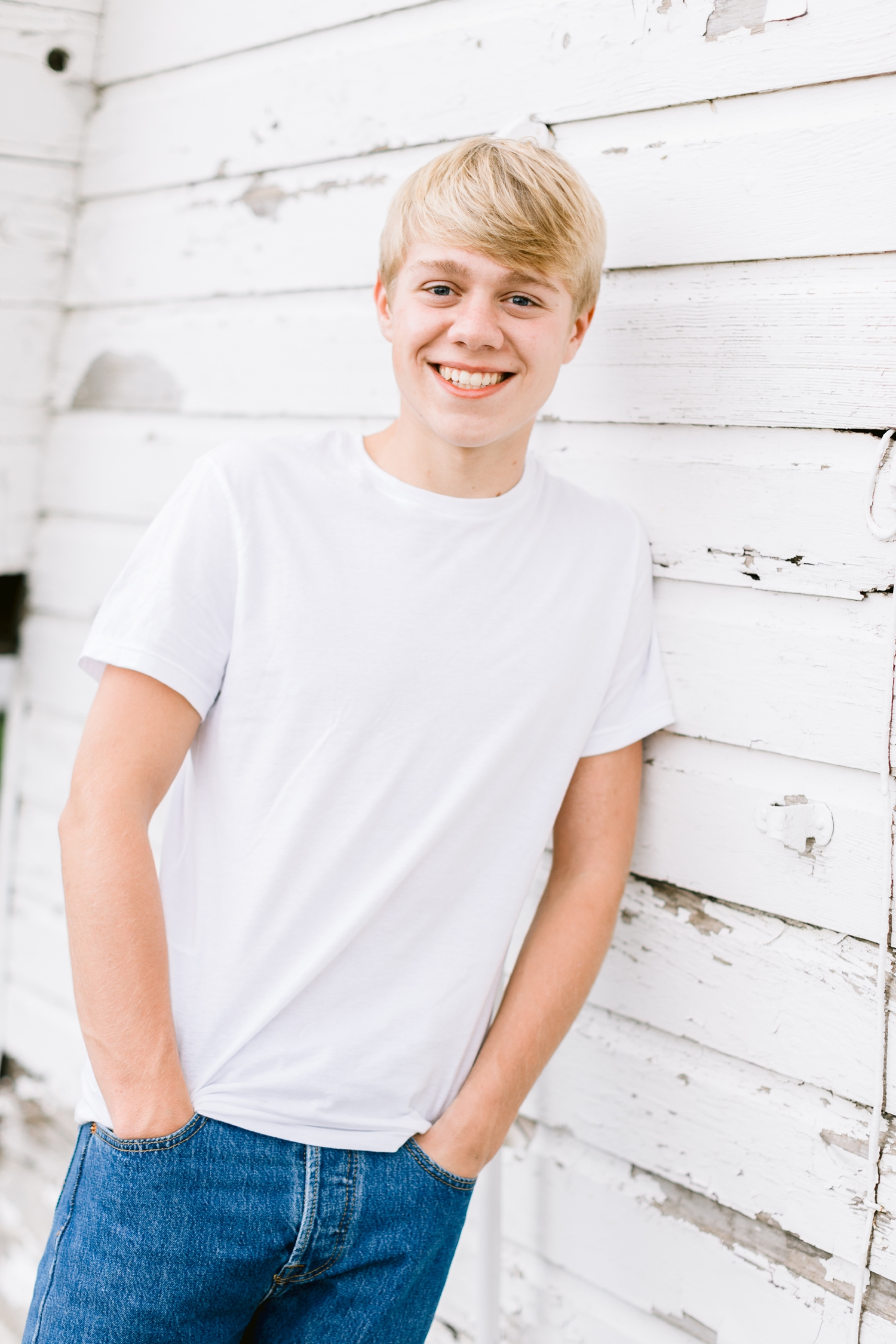 CJ smiles while leaning against an old white barn on his grandpa's farm in northern Iowa | CB Studio