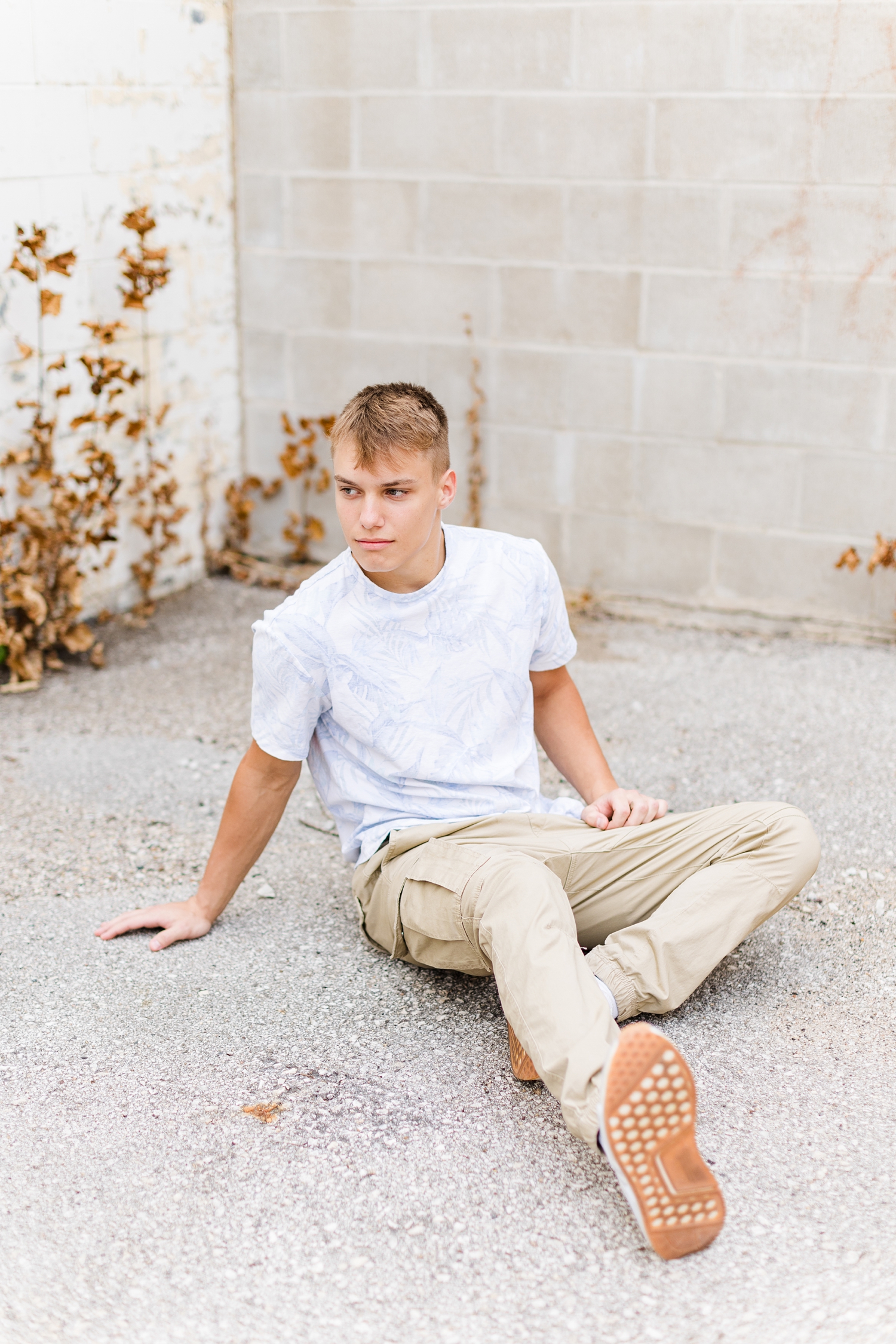Matt sits on pavement in a corner cove of a light brick building in downtown Algona, IA | CB Studio