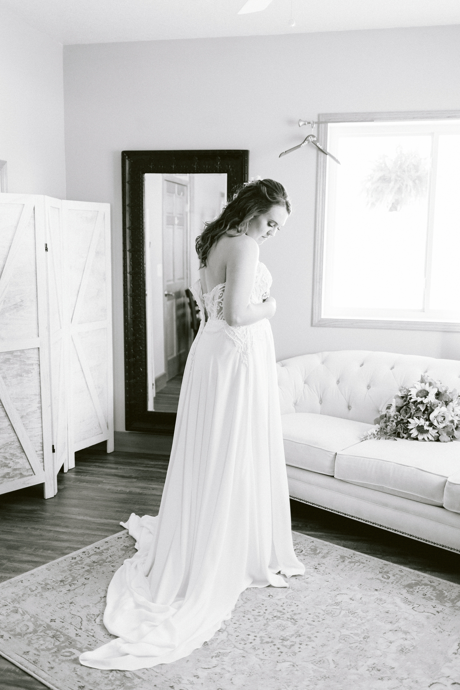 Megan looks down at her wedding gown as she dresses in the bridal suite at Countryside Wedding and Events in Knoxville, IA | A rustic, country wedding with western touches | CB Studio