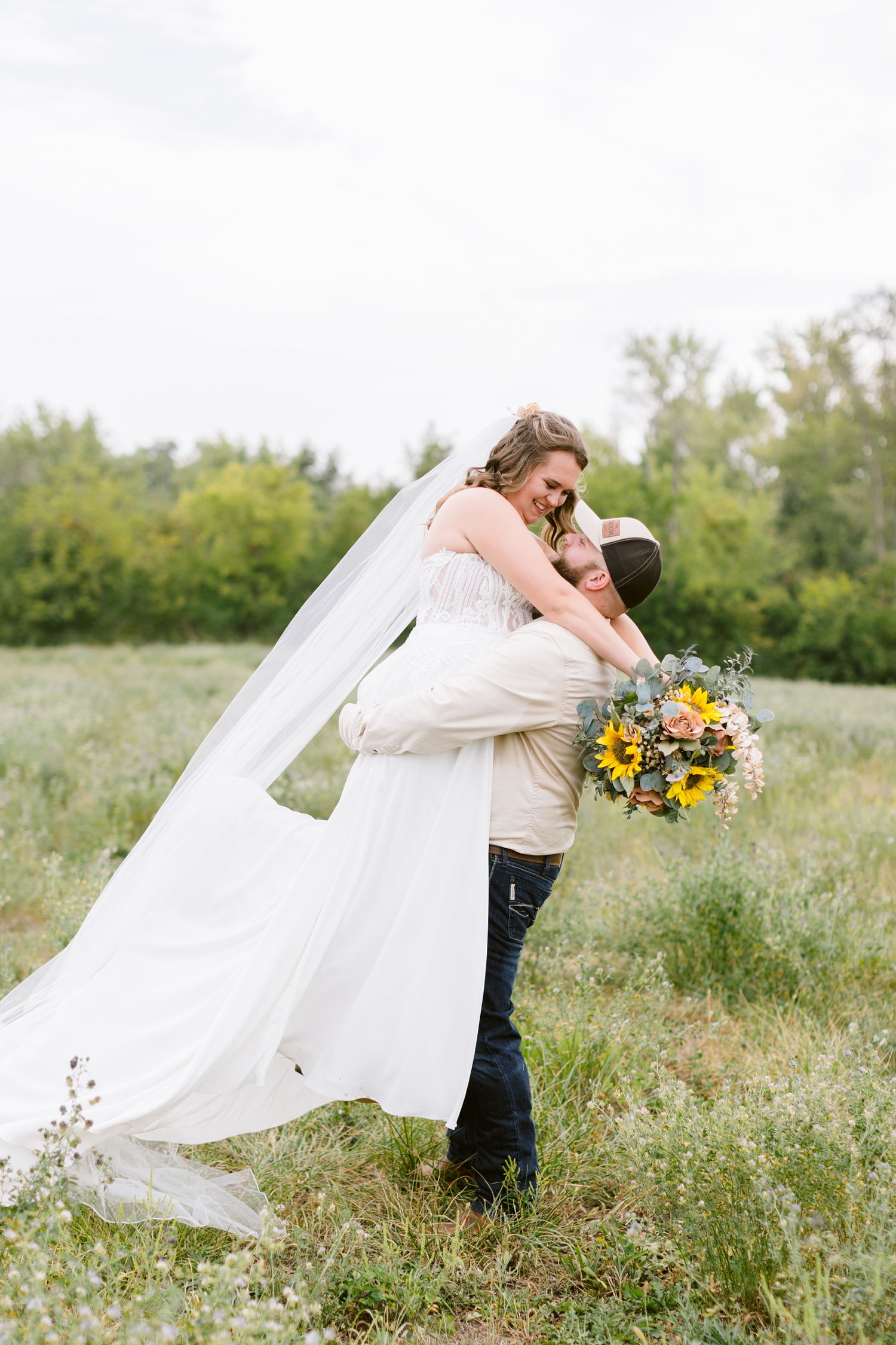 Matt picks up his new bride and spins her around in a grassy field in Knoxville, Iowa | CB Studio