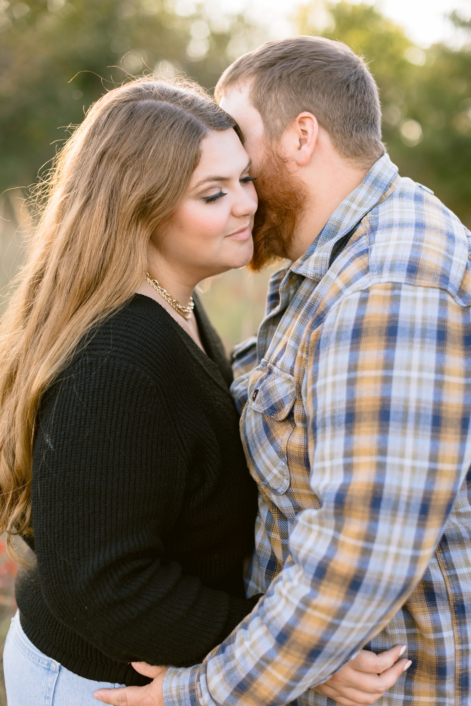 Trent whispers in the ear of his bride-to-be surrounded by fall foliage at Sheldon Park in Humboldt, IA | CB Studio