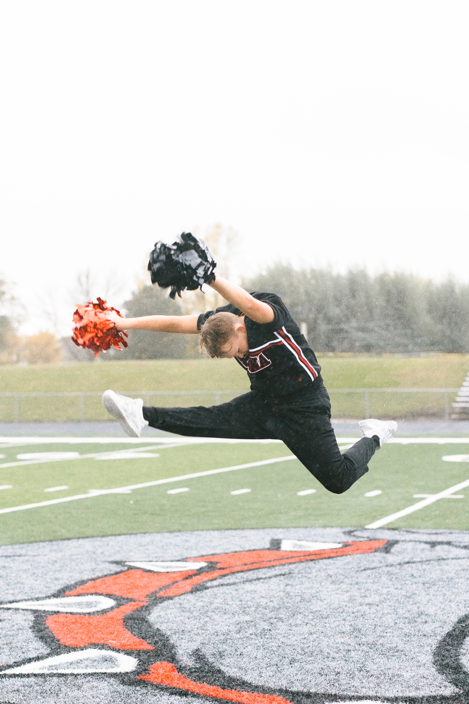 Seth performs a hurdler/herky jump in the middle of the Algona football field in the pouring rain | CB Studio