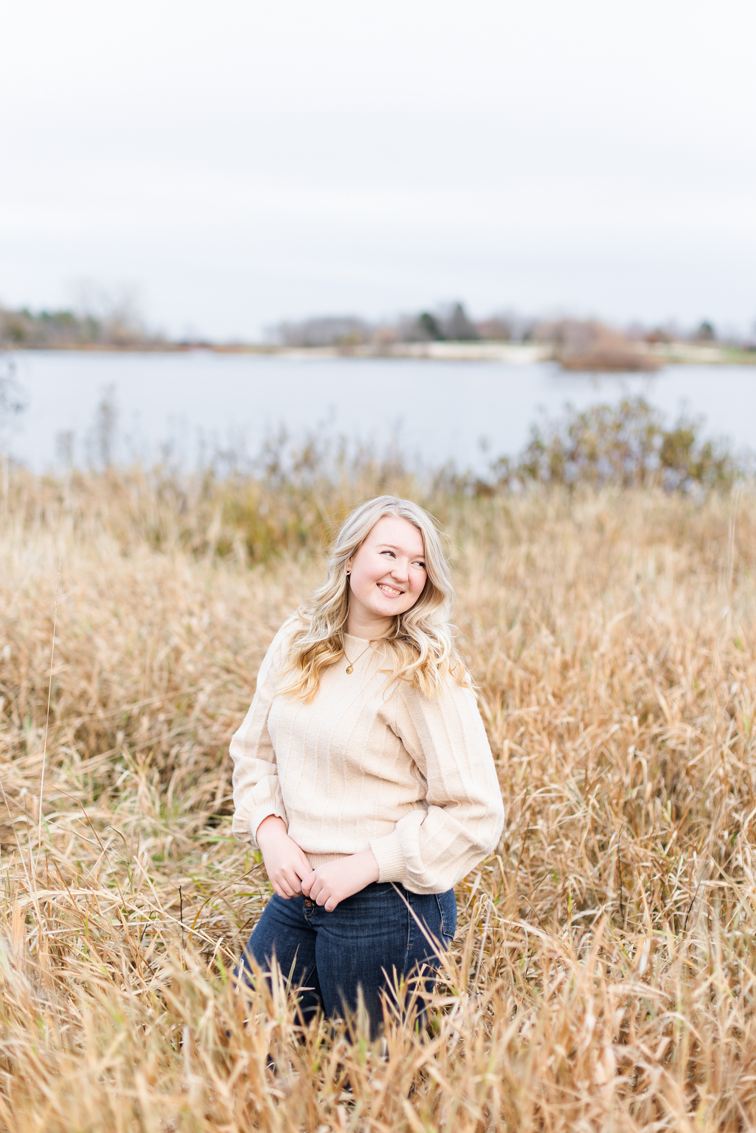 Jayden looks over her shoulder and smiles as she stands in a tall grassy field | CB Studio
