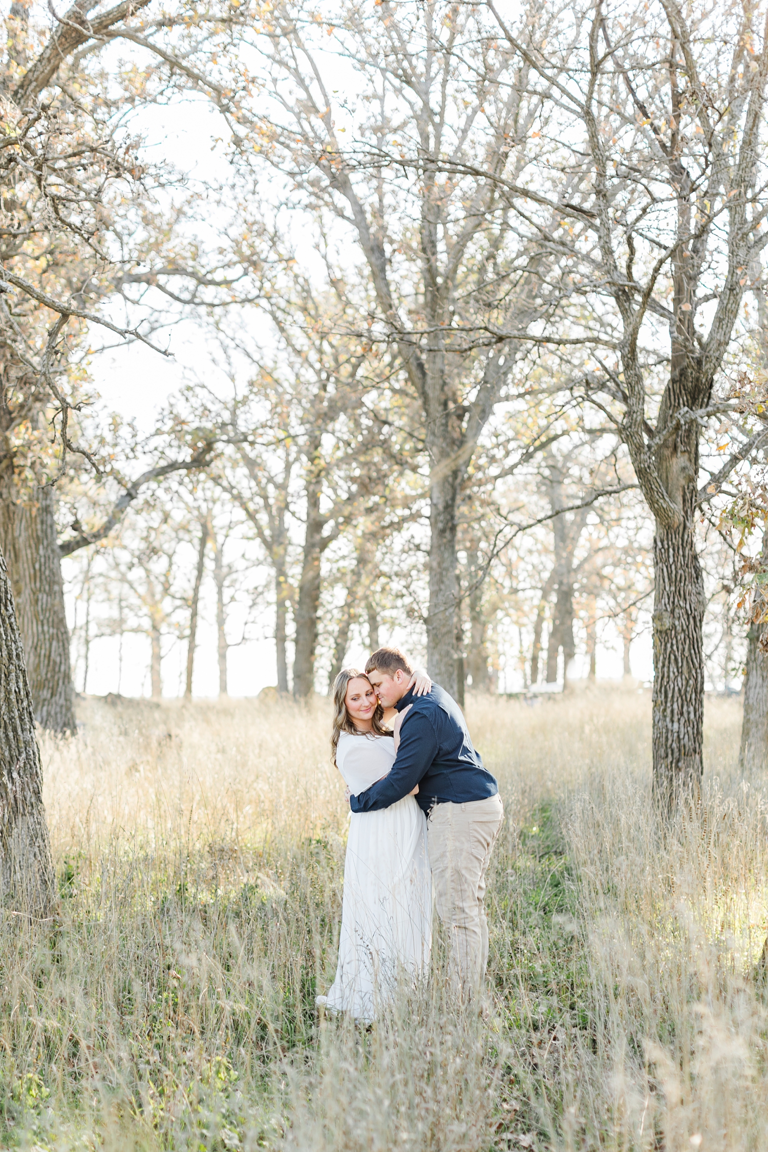 Taylor nuzzles Shelby in the middle of a field of oak trees in the fall | CB Studio