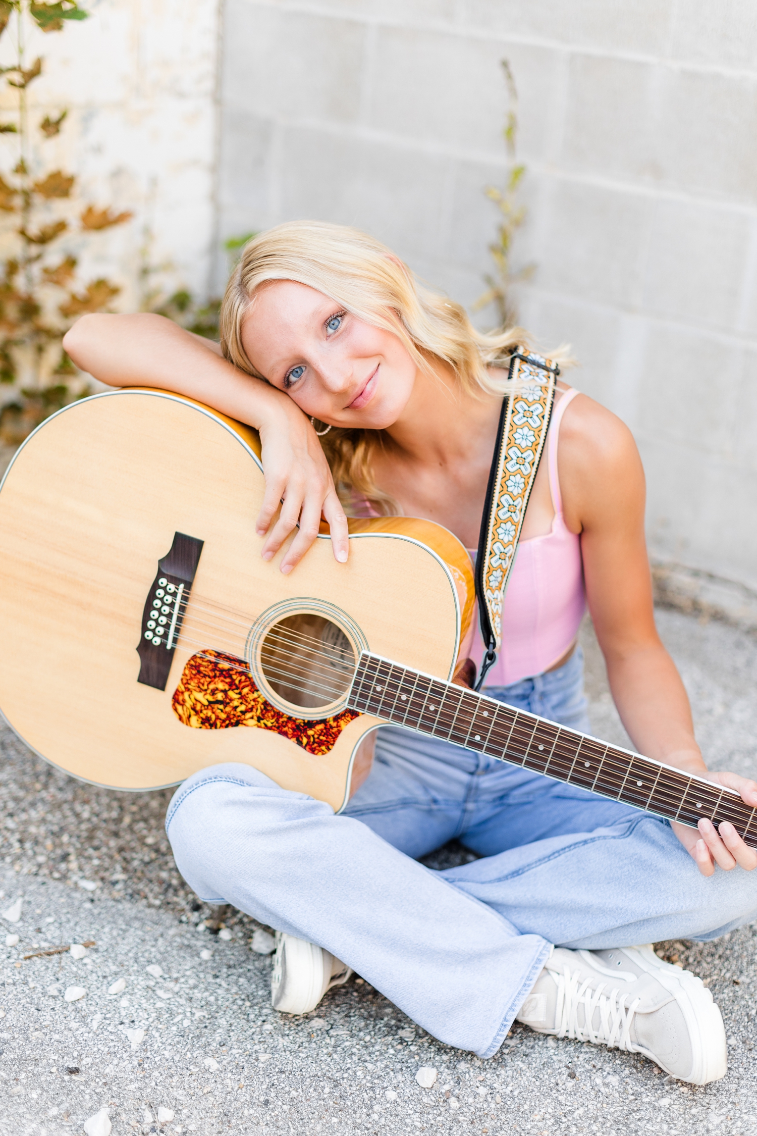 Avery sits on the concrete and leans on her guitar, in downtown Algona, IA | CB Studio