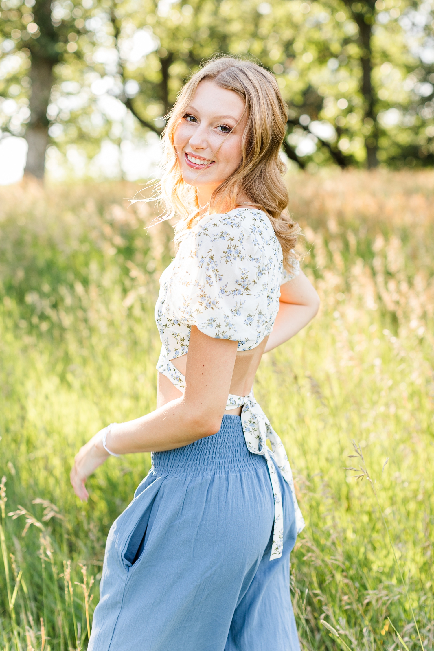 Ryley walks away in a grassy field as she looks back and smiles | CB Studio