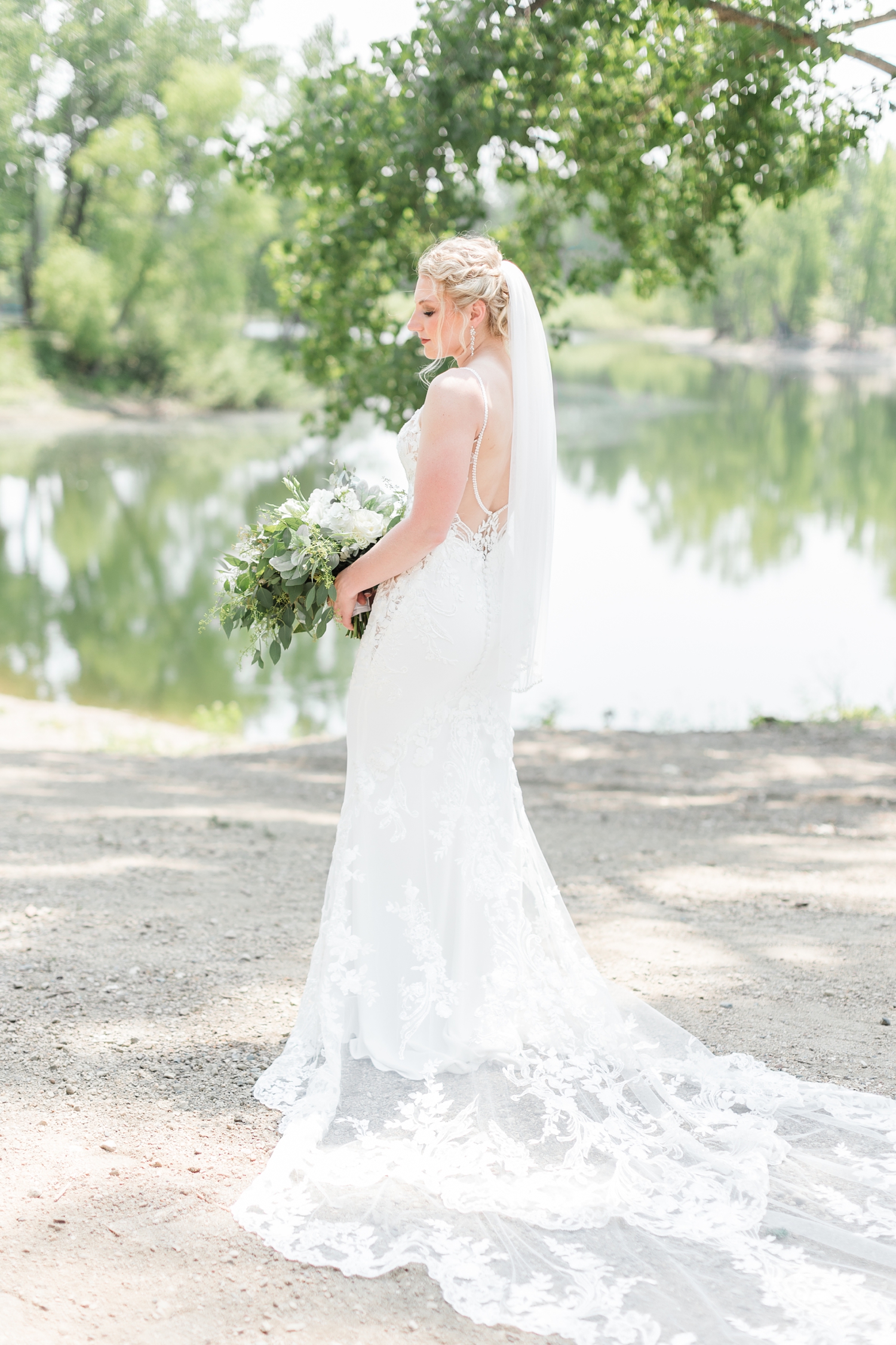 Alli stuns in her Enzoani bridal gown as she stands next to the lake at Wildhaven | CB Studio