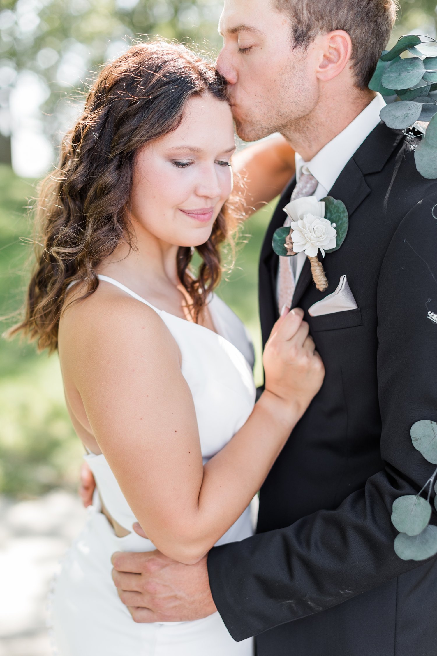 Grant kisses his new bride on the forehead as they embrace in the trees of Five Island Lake Campground | CB Studio