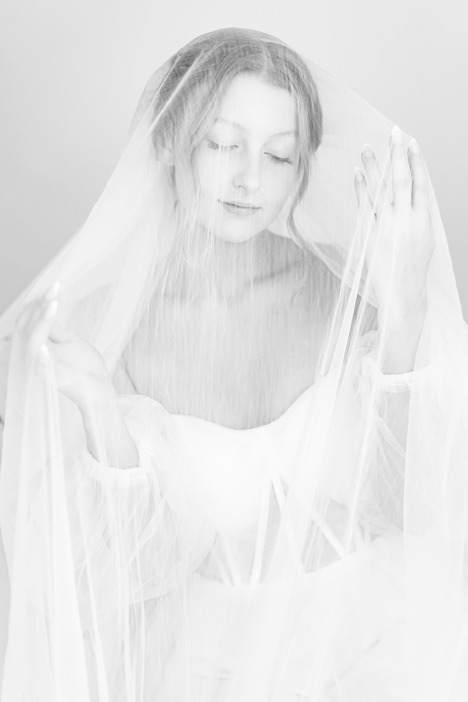 Bride, Ryley, draped in her veil as her hands gently glide down the inside of her veil | CB Studio