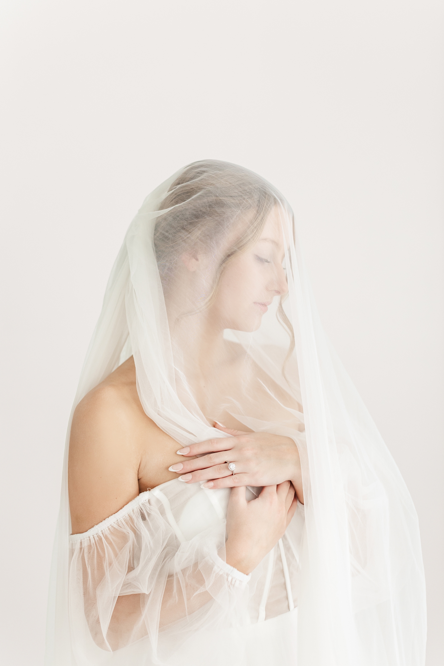 Bride, Ryley, stands gracefully as she holds her cathedral length veil as it is draped over her | CB Studio