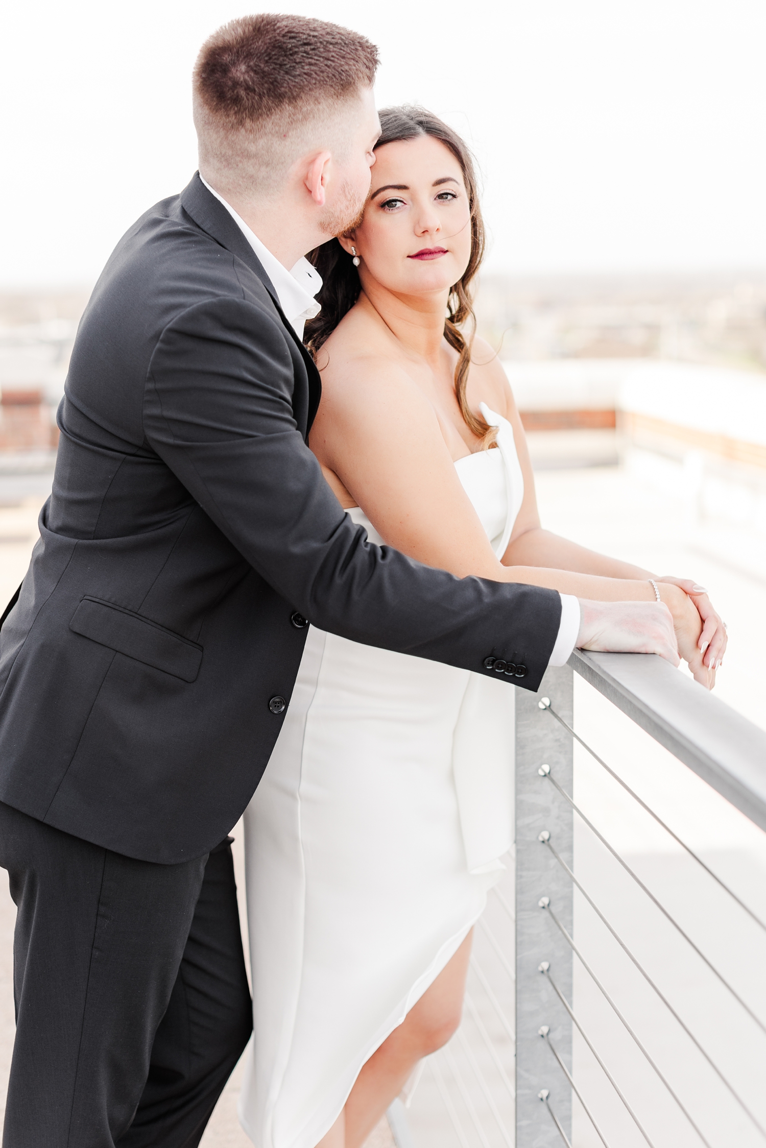 Jenna and her fiance, Dustin, lean over a metal railing on the rooftop of the The Equitable Building in Des Moines, IA | CB Studio