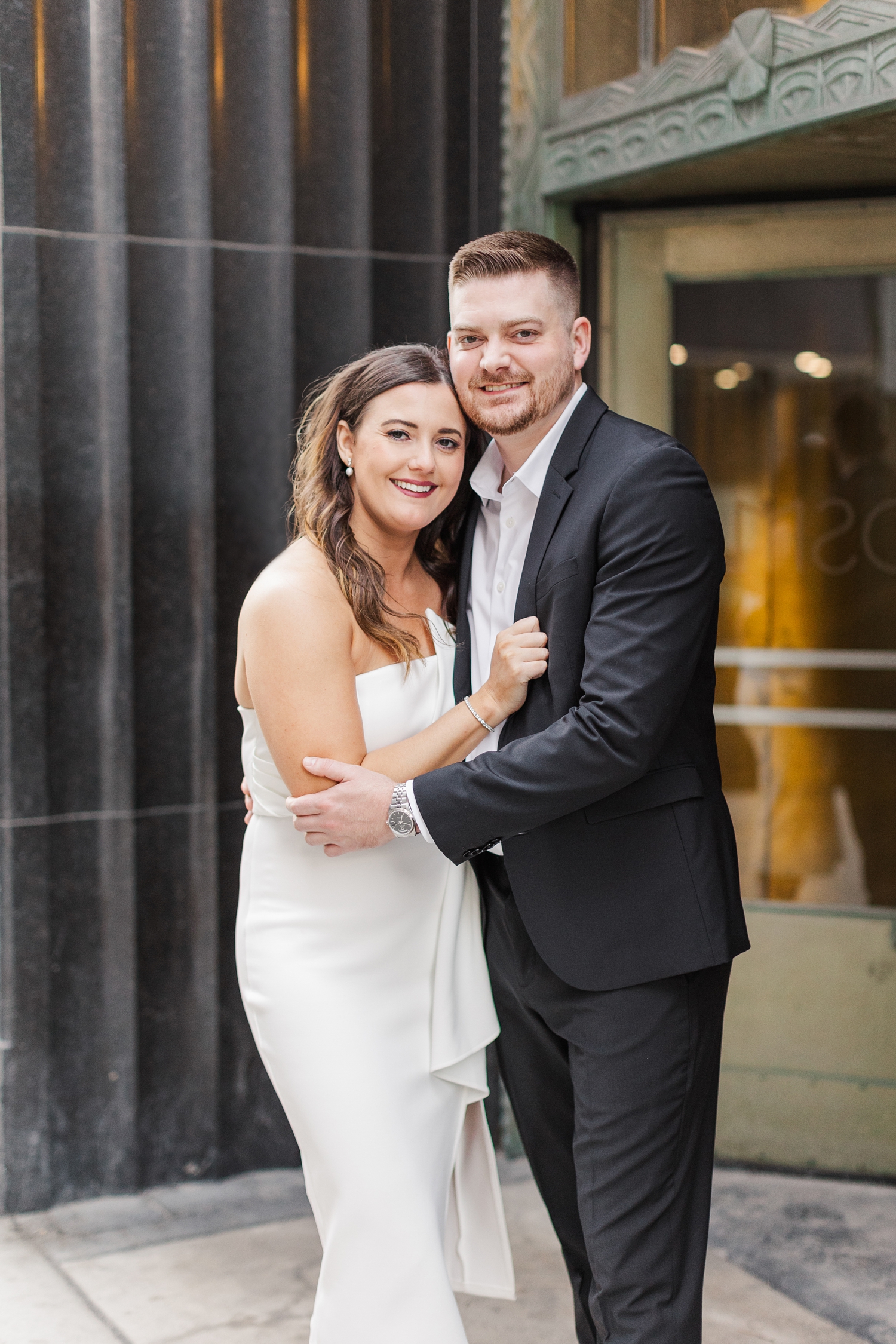 Jenna and Dustin embrace in front of a beautiful architectural building in downtown Des Moines, IA | CB Studio