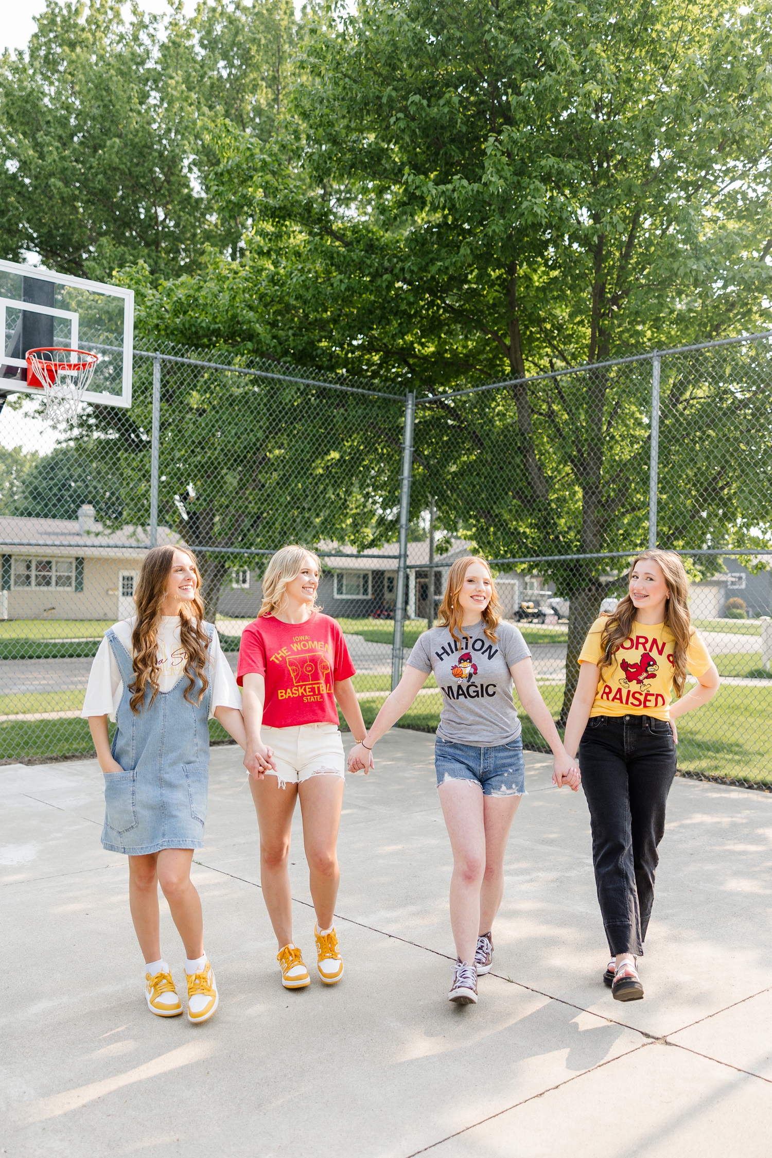Four TEAM 25 girls, wearing Iowa State clothing, walk together hand and hand on an outdoor basketball court | CB Studio