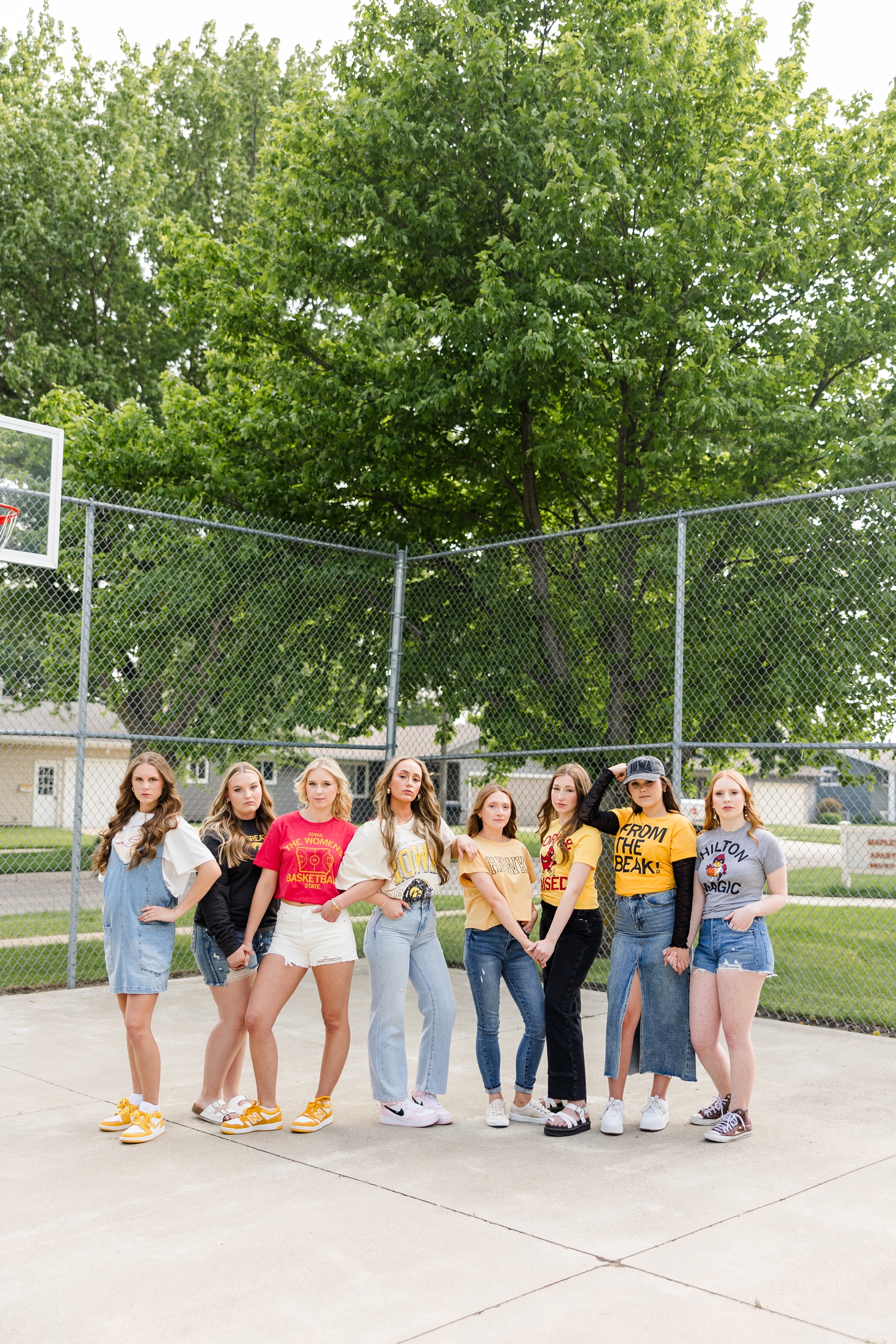 TEAM 25, all wearing Iowa or Iowa State clothing, model pose in a straight line in an outdoor basketball court | CB Studio