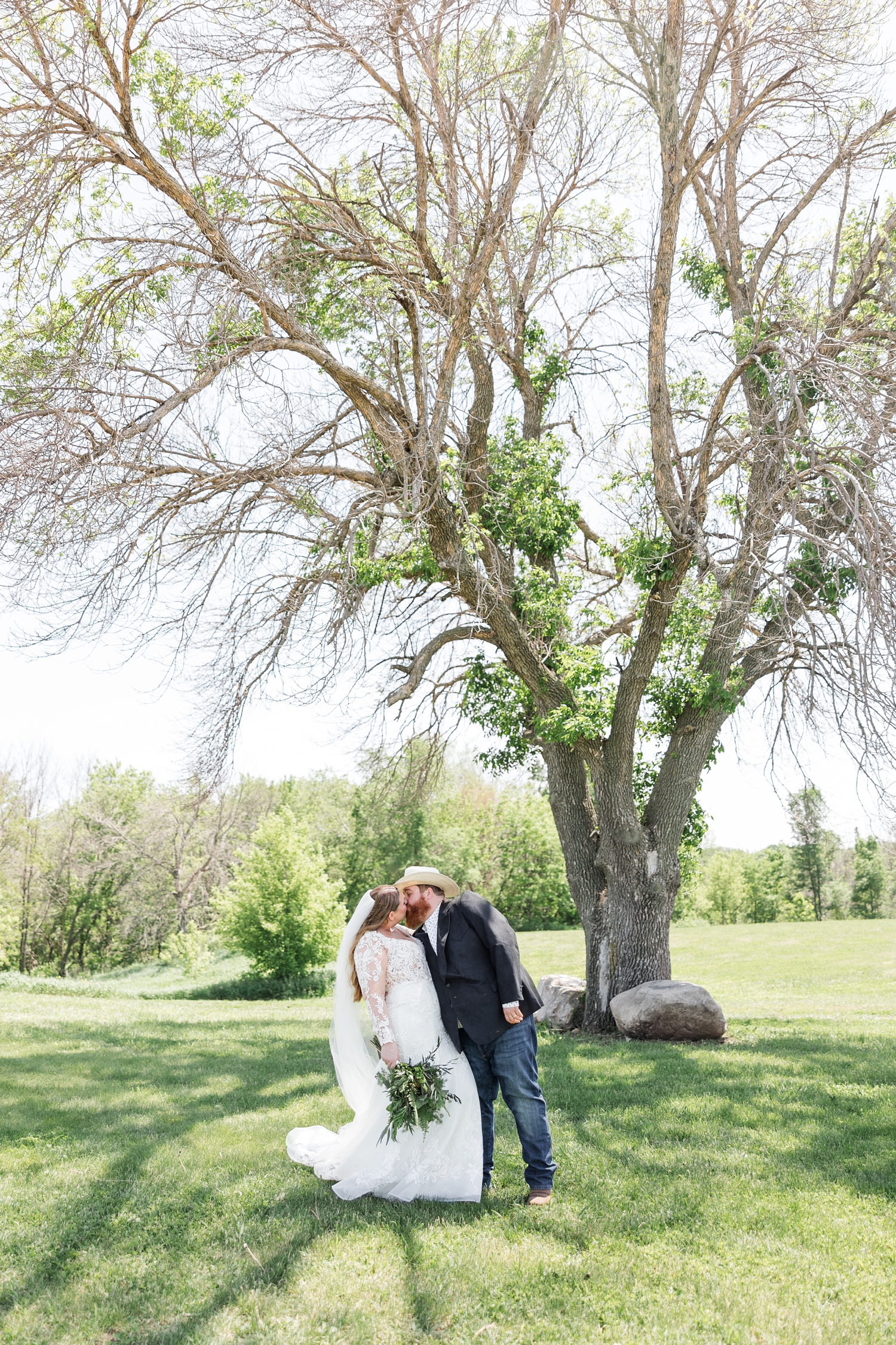 Trent kisses his new bride, Neely, under a beautiful oak tree at Lizard Creek Ranch in Fort Dodge, IA | CB Studio