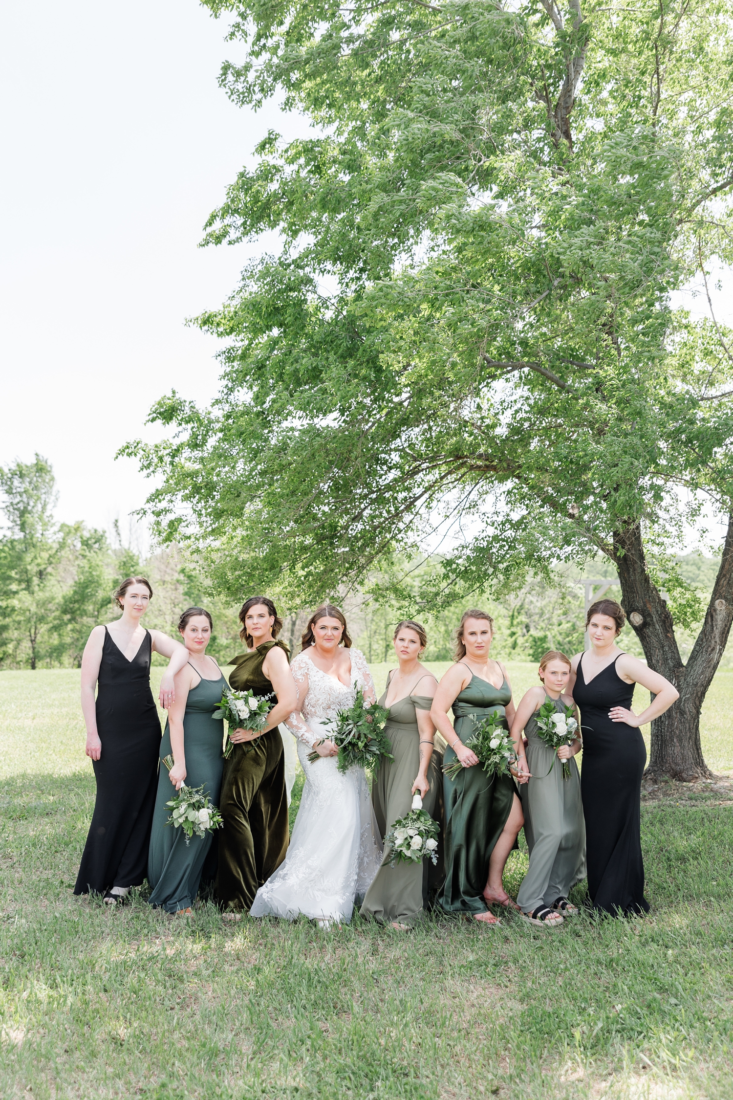 Neely model poses with her bridesmaids all wearing shades of olive green at Lizard Creek Ranch in Fort Dodge, IA | CB Studio 