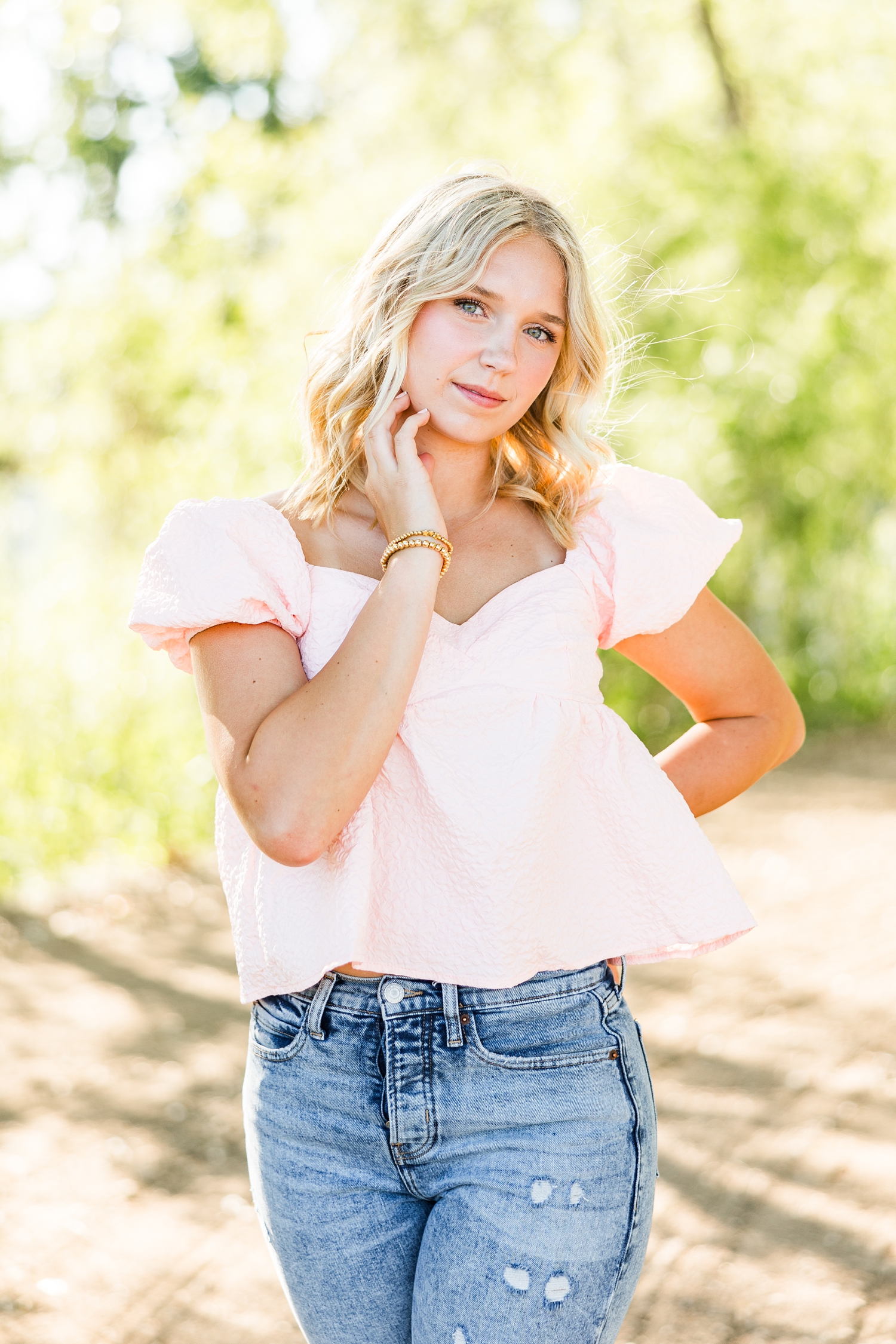 Addi, wearing a pink top and jeans, looks at the camera in a blank stare at Wild Haven | CB Studio