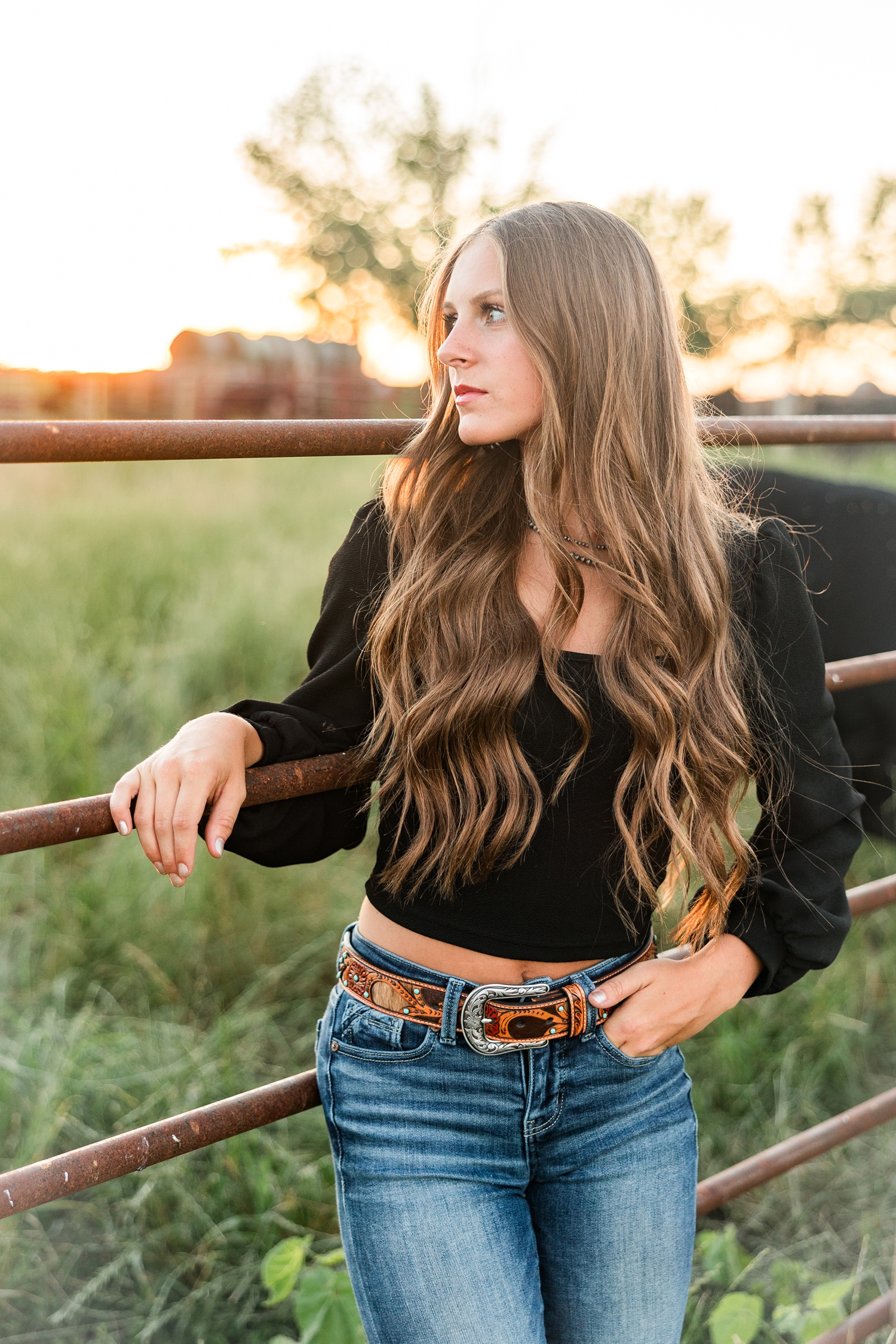 Ashton leans against a cattle gate on her Iowa Farm at golden hour | CB Studio