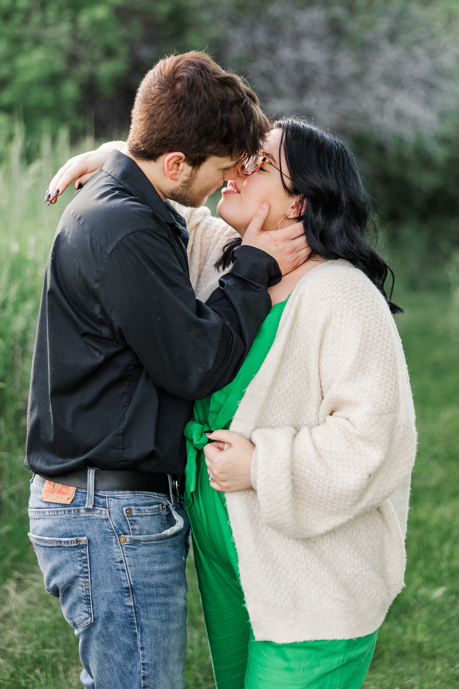 Brandon and Kylie slowly lean in for a kiss in a grassy pasture at Water's Edge Nature Center | CB Studio