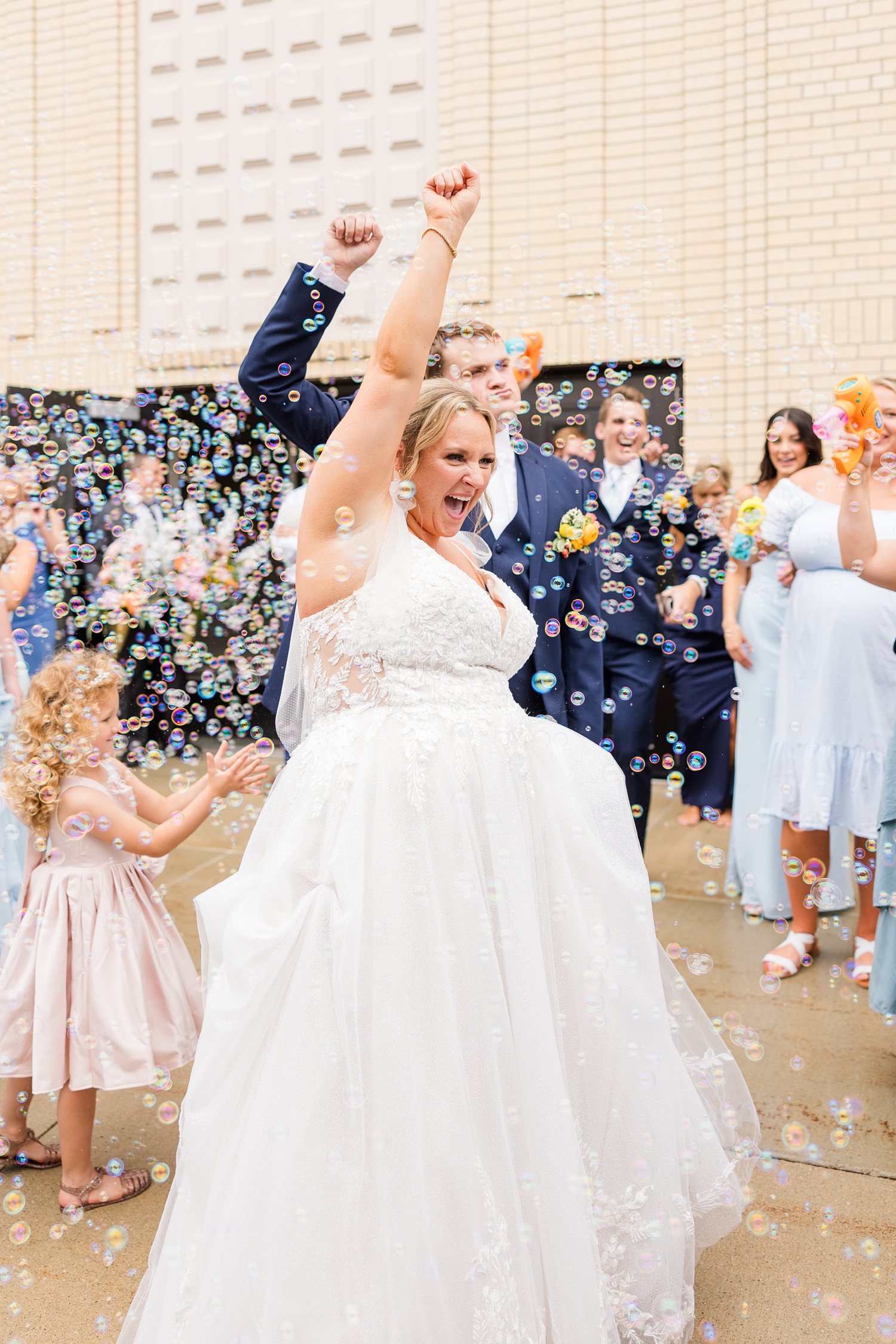 Shelby and Taylor cheer and celebrate completely surrounded by bubbles as they exit for St John the Baptist Catholic Church in Bancroft, IA | CB Studio