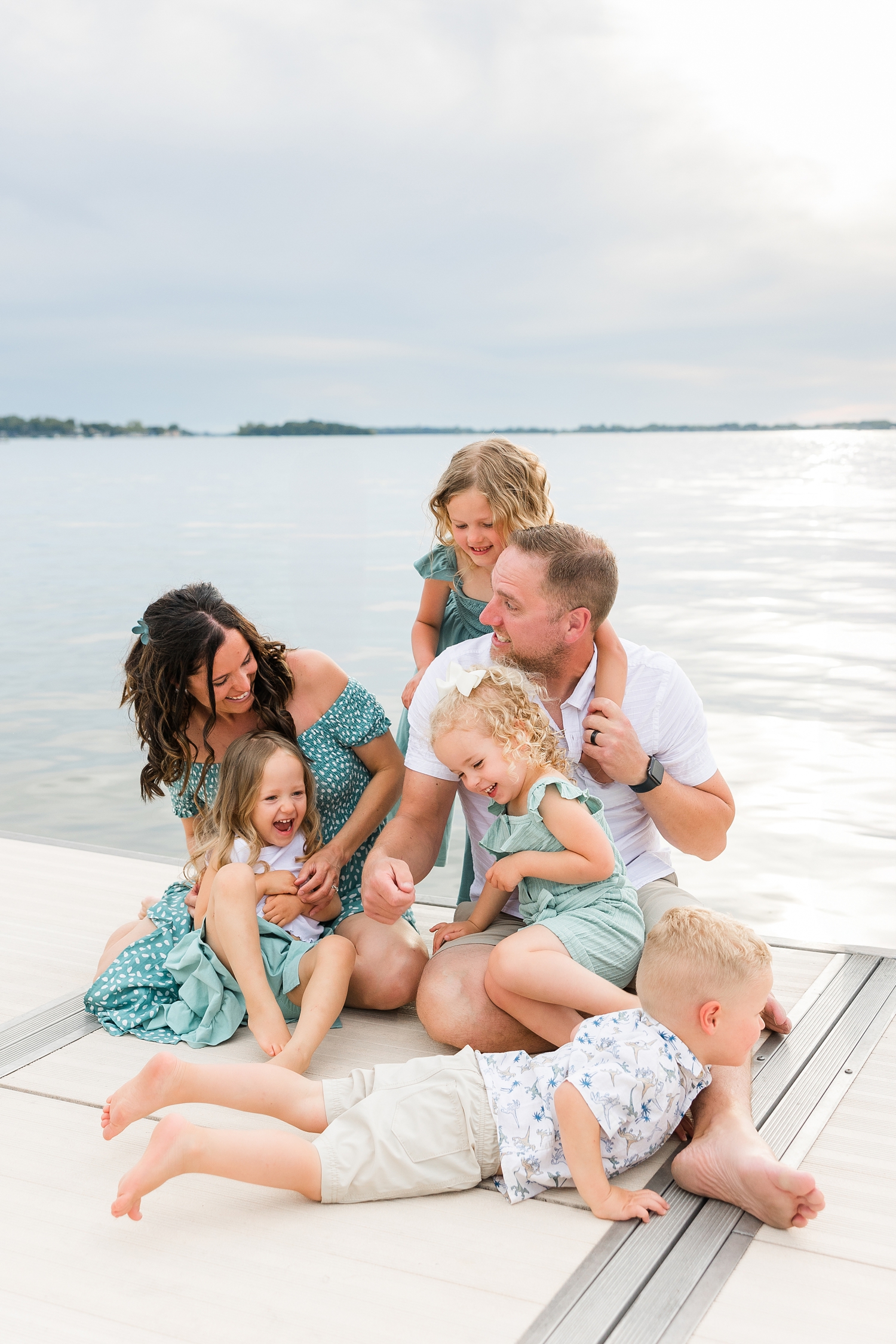 Family of 6 sit on the dock on Clear Lake, IA as they tickle their 4 children | CB Studio