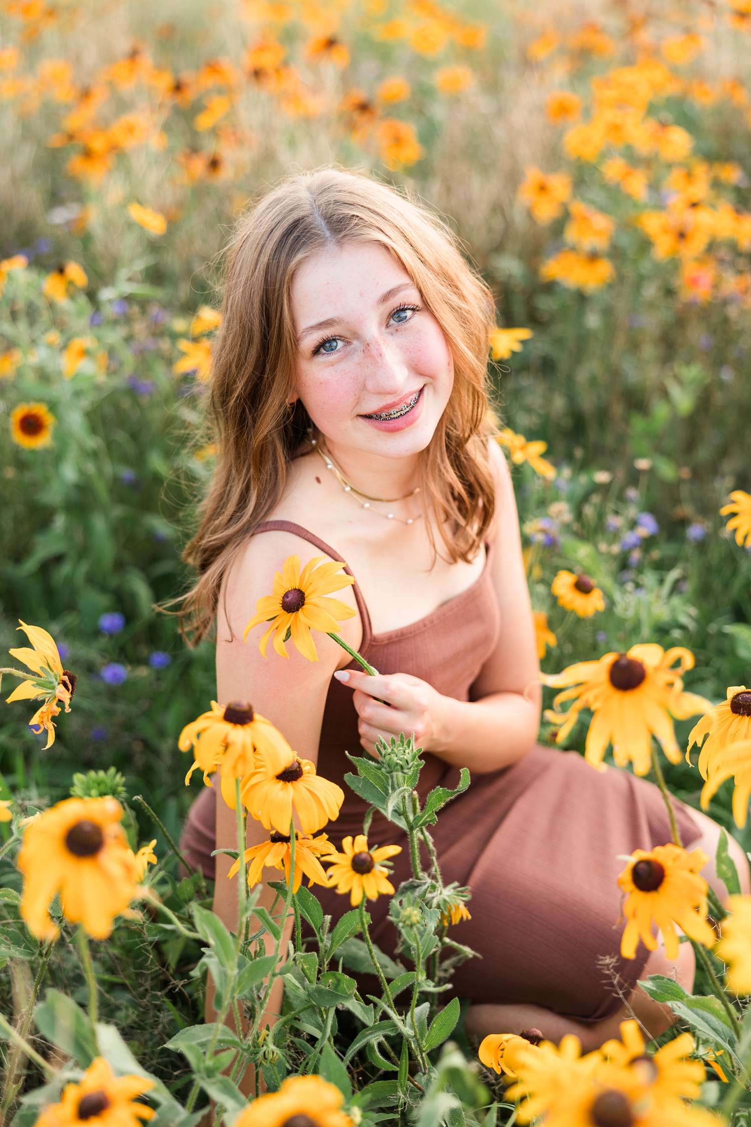 Bre, wearing a brown body con dress, sits in a wildflower field surrounded by Black-eyed Susans at golden hour | CB Studio