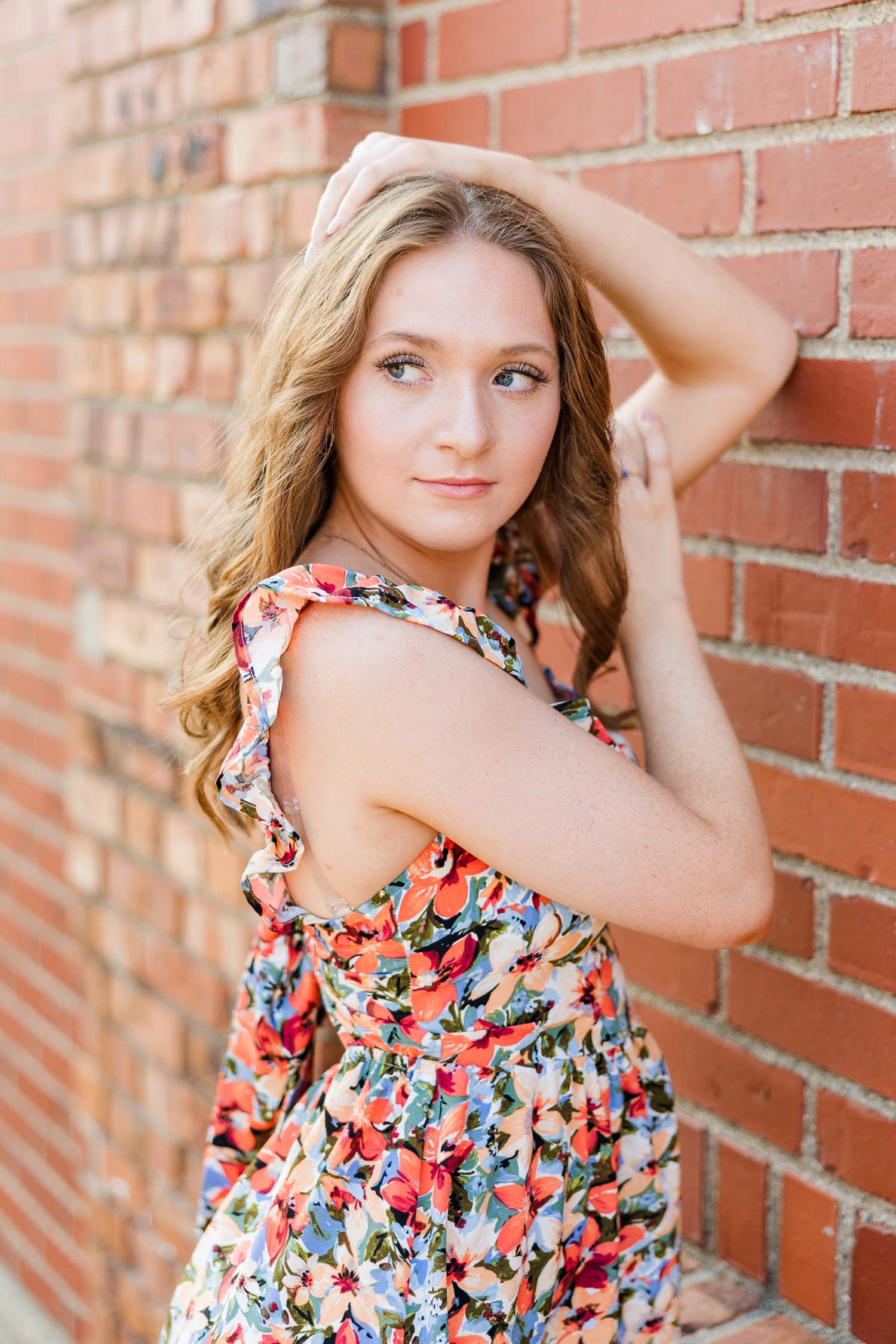 Izzie looks over shoulder as she leans her elbows on a brick wall in downtown Algona, IA | CB Studio