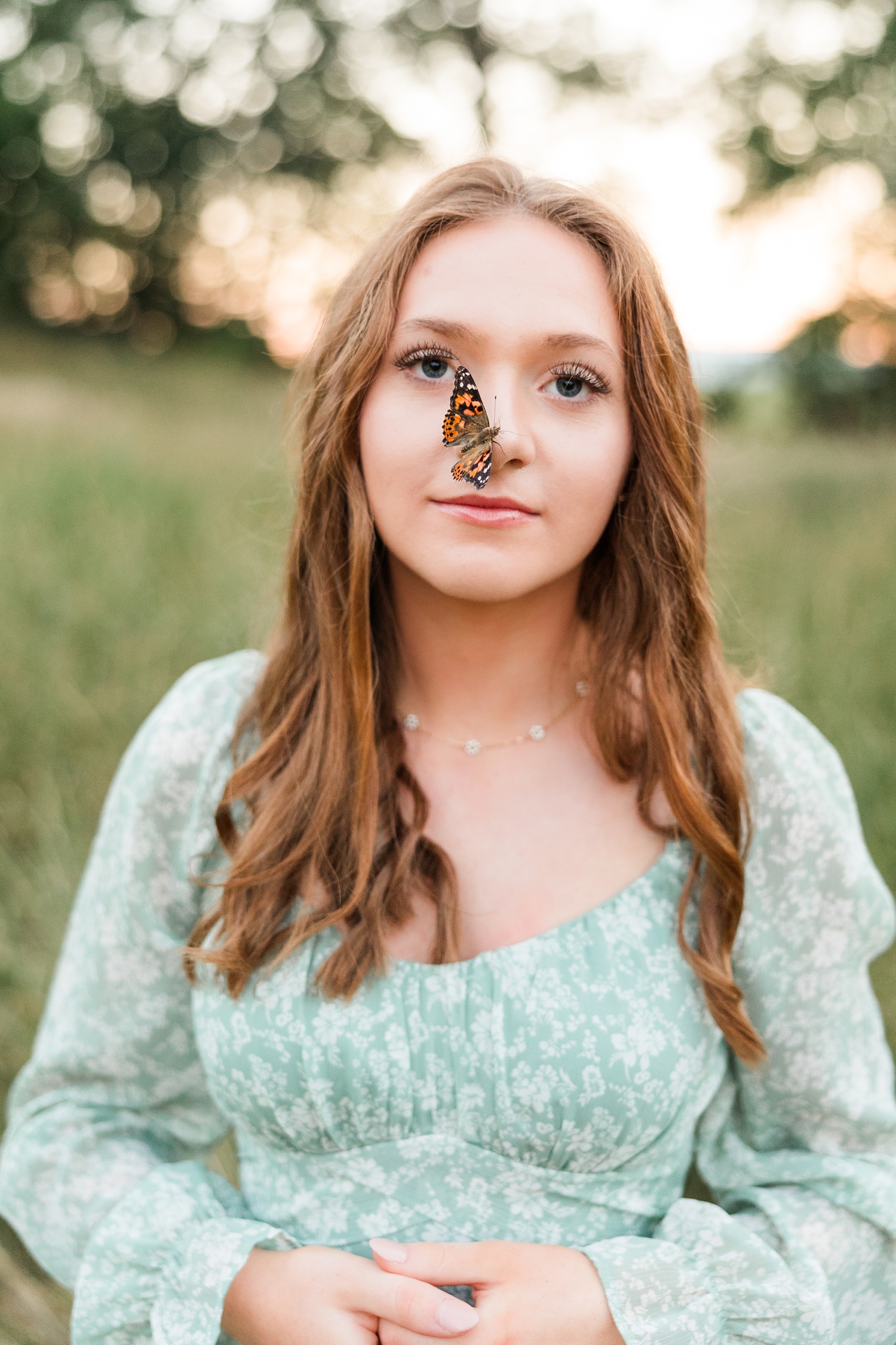 Izzie stands in a grassy pasture at golden hour as a butterfly sits quietly on her nose | CB Studio