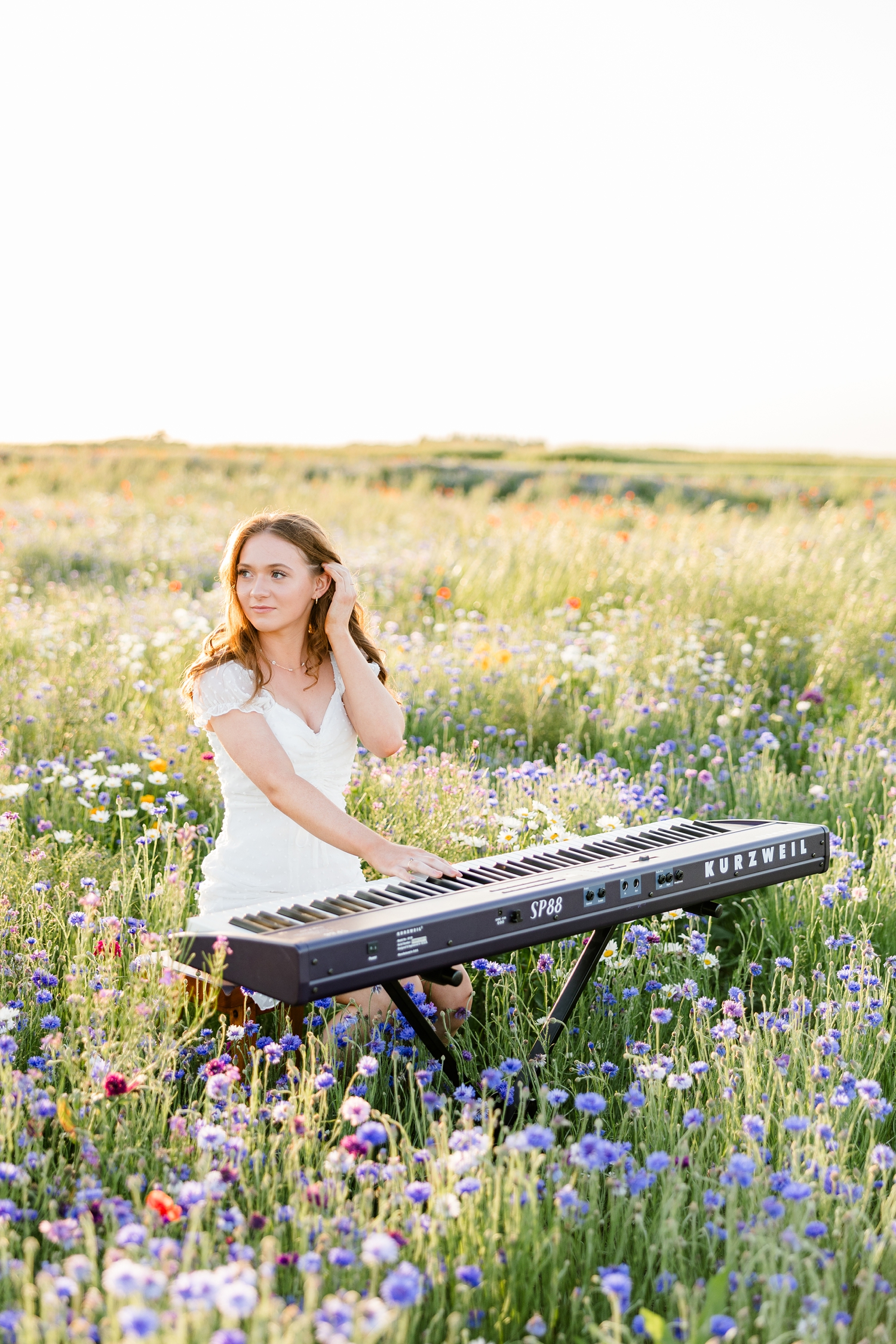 Izzie plays her piano in a field on wildflowers at sunset | CB Studio