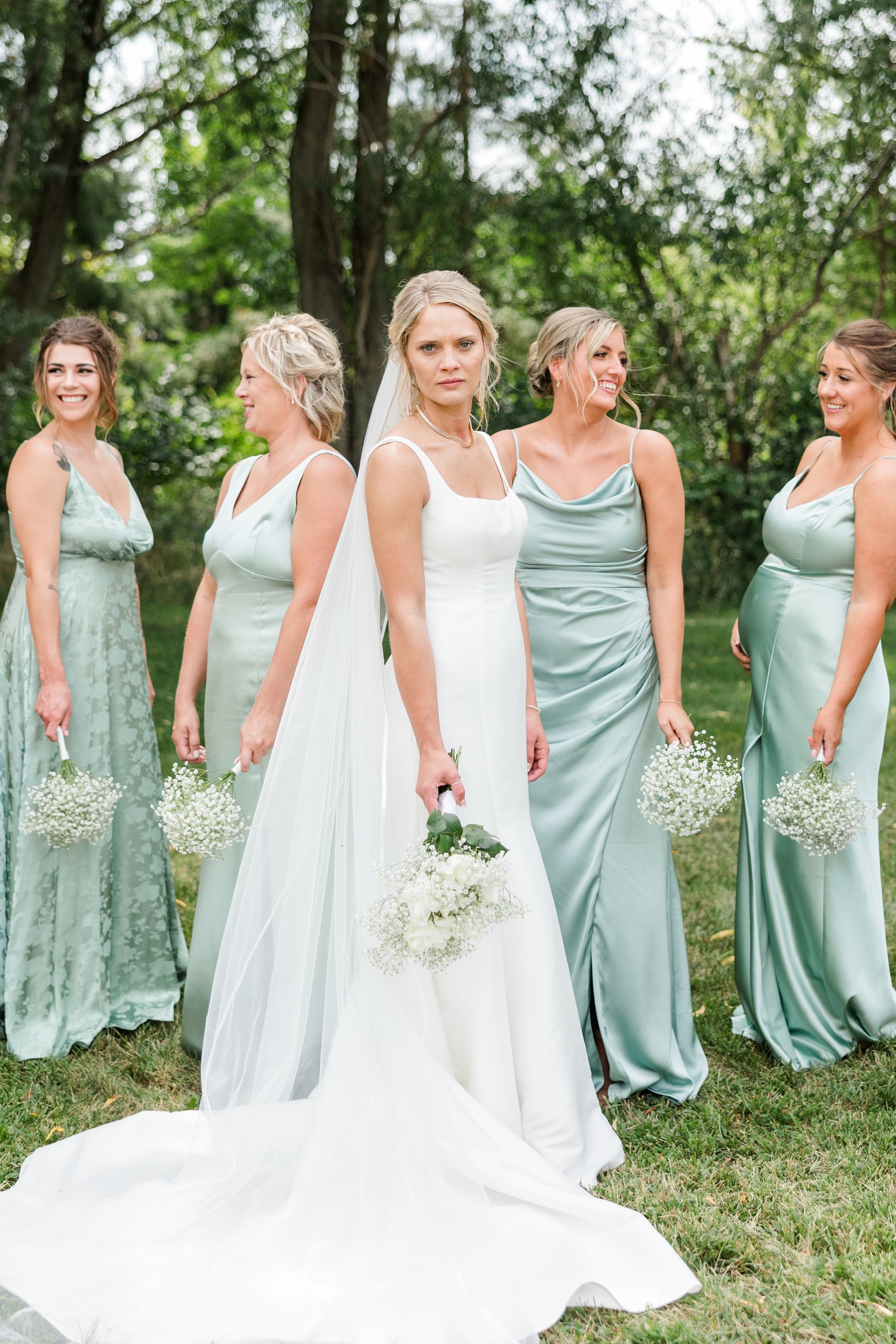 Nicole blank stares straight ahead while her bridesmaids smile at each other slightly behind her | CB Studio