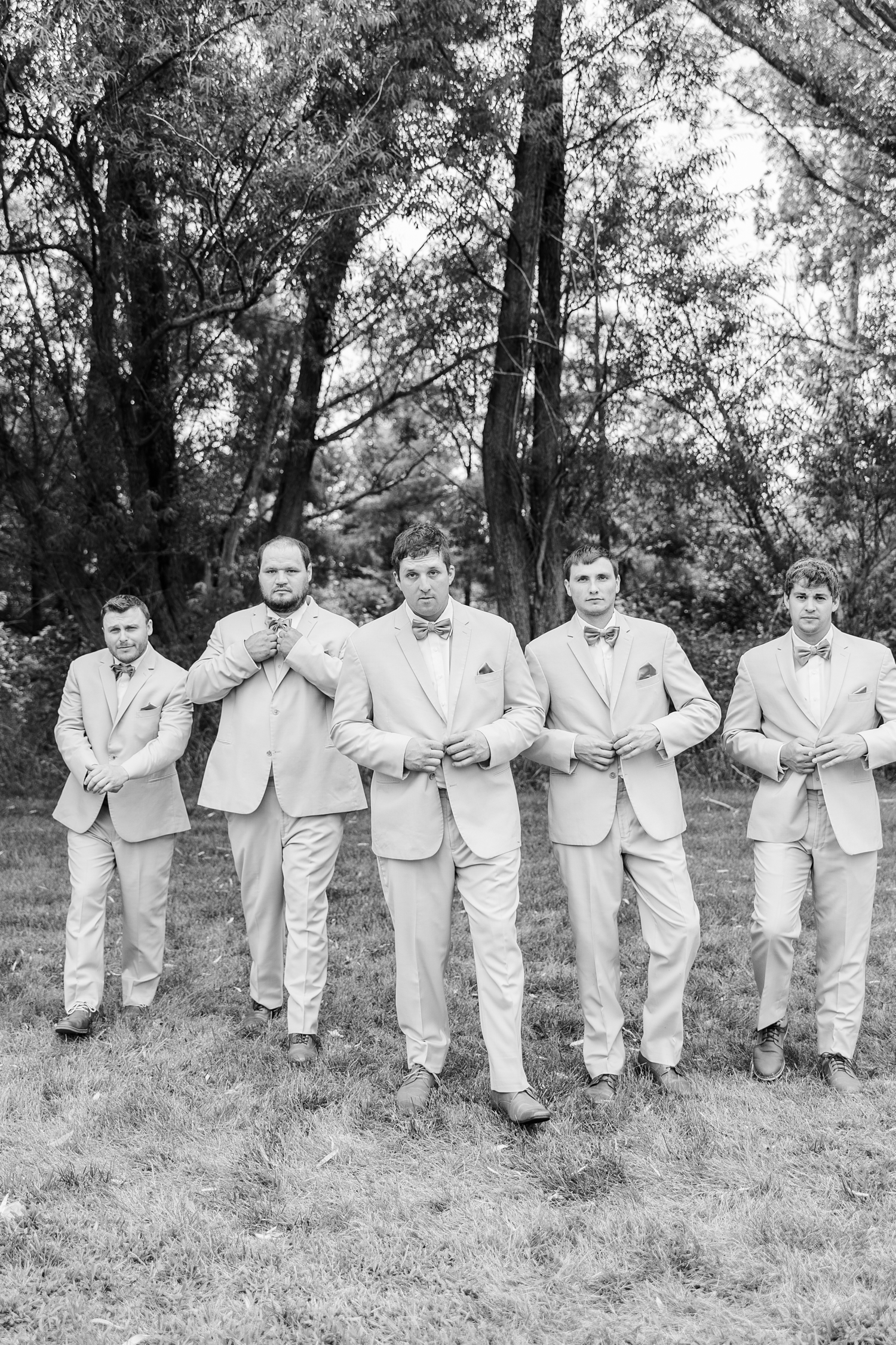 Reed and his groomsmen walk forward stoically as they adjust buttons and ties | CB Studio