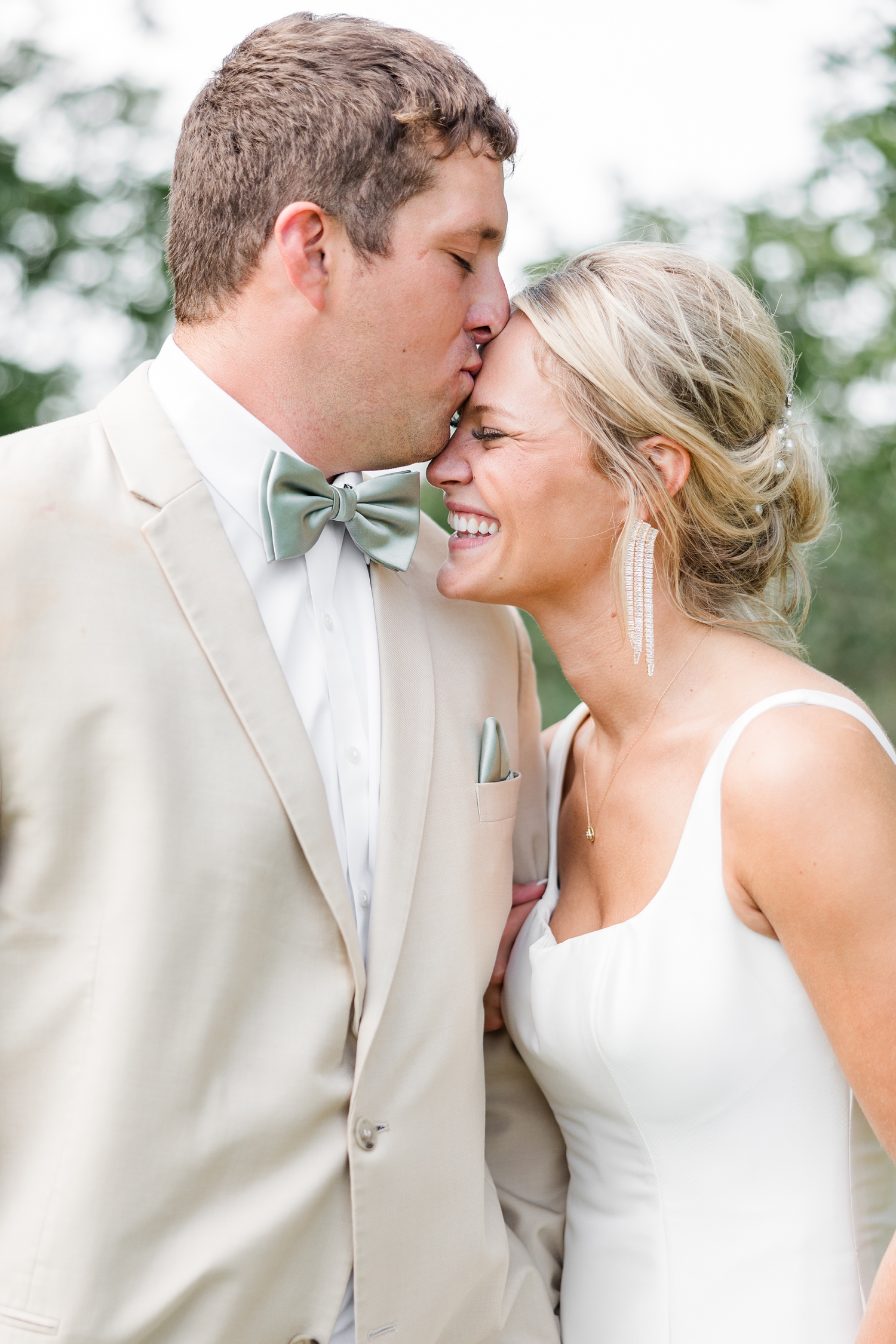 Reed kisses his bride's, Nicole, forehead while she laughs | CB Studio