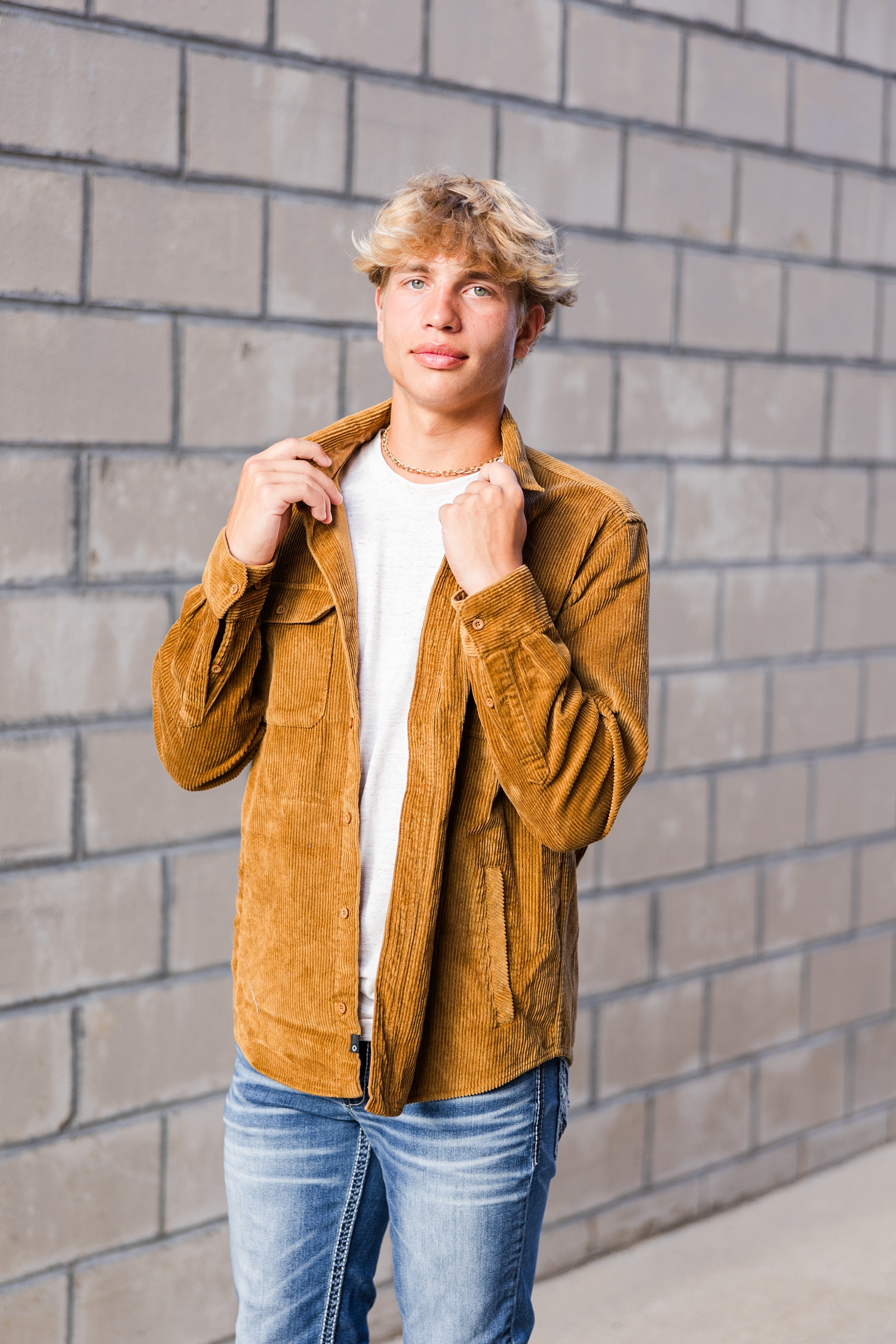 Tyler adjust the collar of his camel corduroy jacket in an alley way in downtown Algona, IA | CB Studio