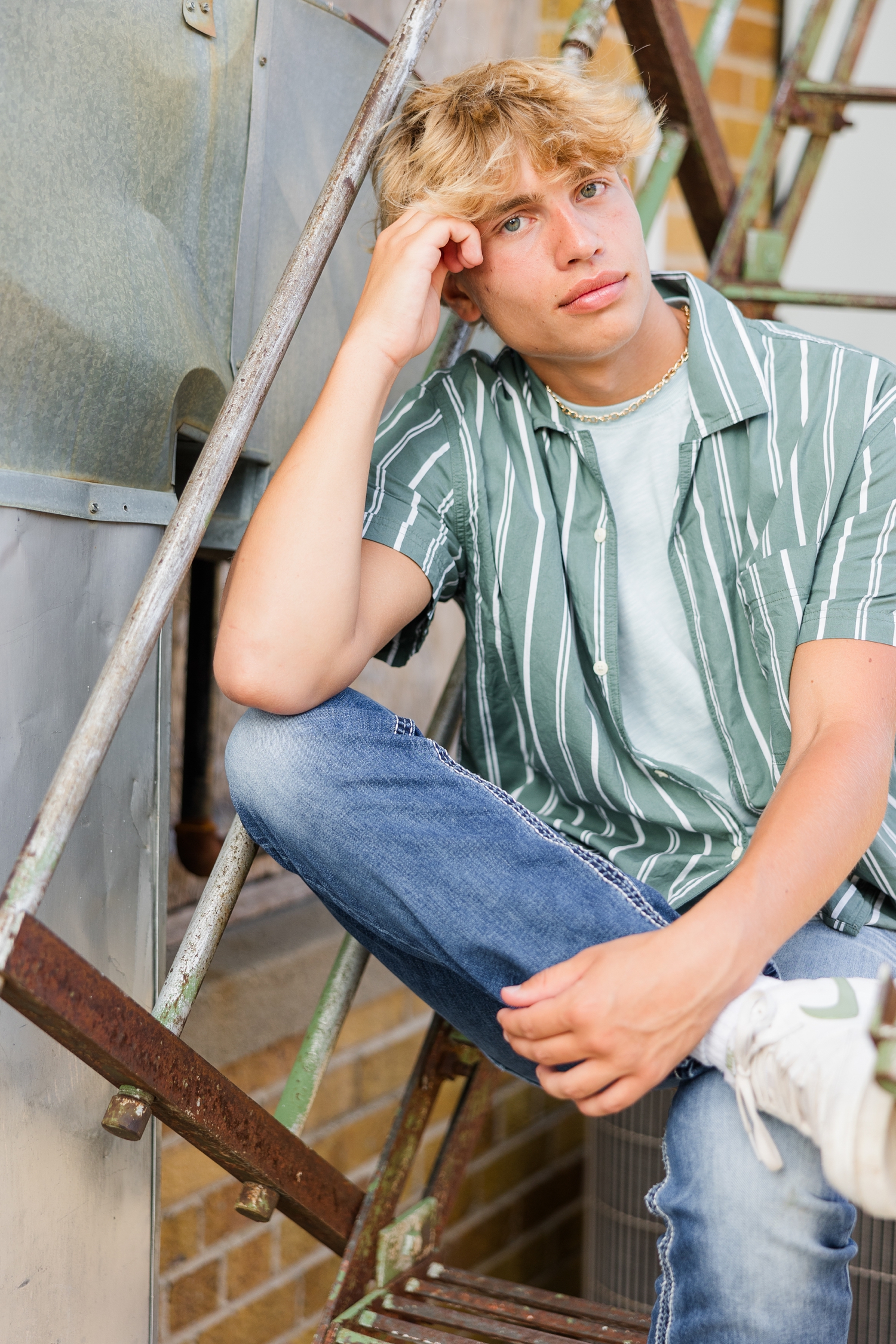 Tyler sits on a rustic metal staircase in downtown Algona, IA | CB Studio