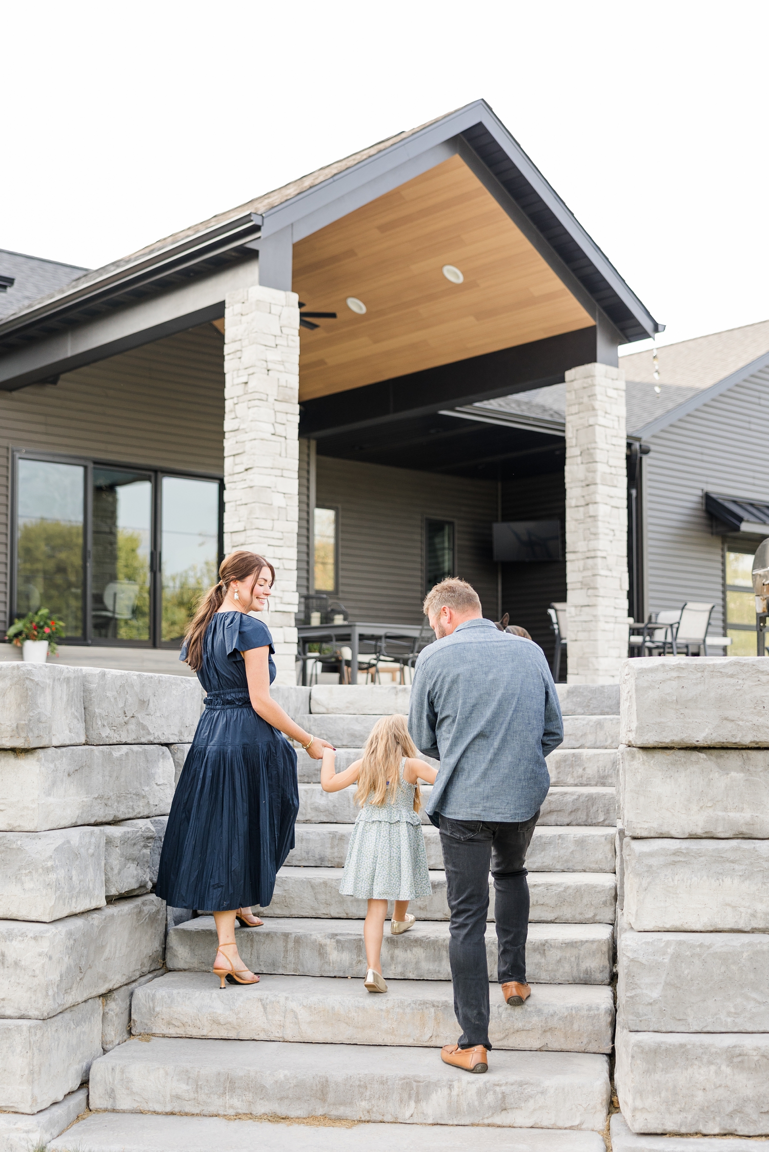 The Arndorfers walk up the stone steps to their back patio in their new, modern home for an in-home lifestyle family photoshoot | CB Studio