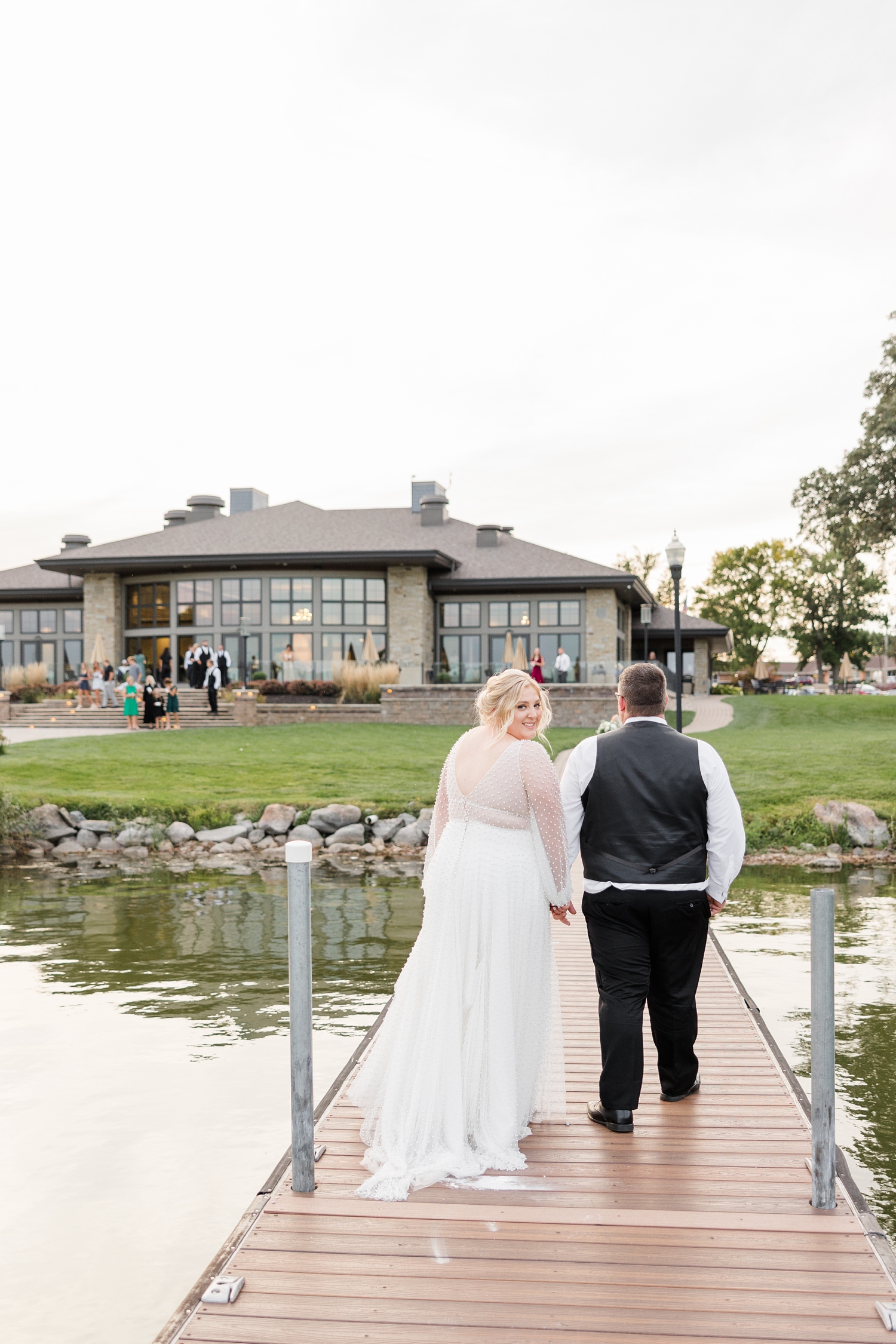 Halie looks back and smiles as Nick leads her on the dock to their wedding reception at The Shores at Five Island | CB Studio