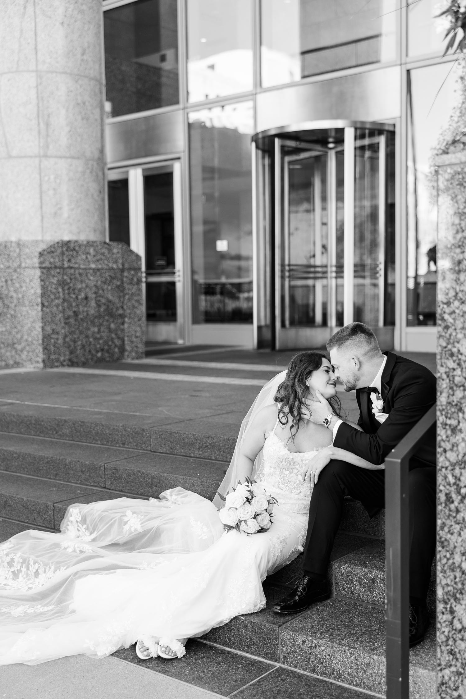 Dustin pulls Jenna in slowly for a kiss as they sit on the steps of 801 Grand in downtown Des Moines | CB Studio