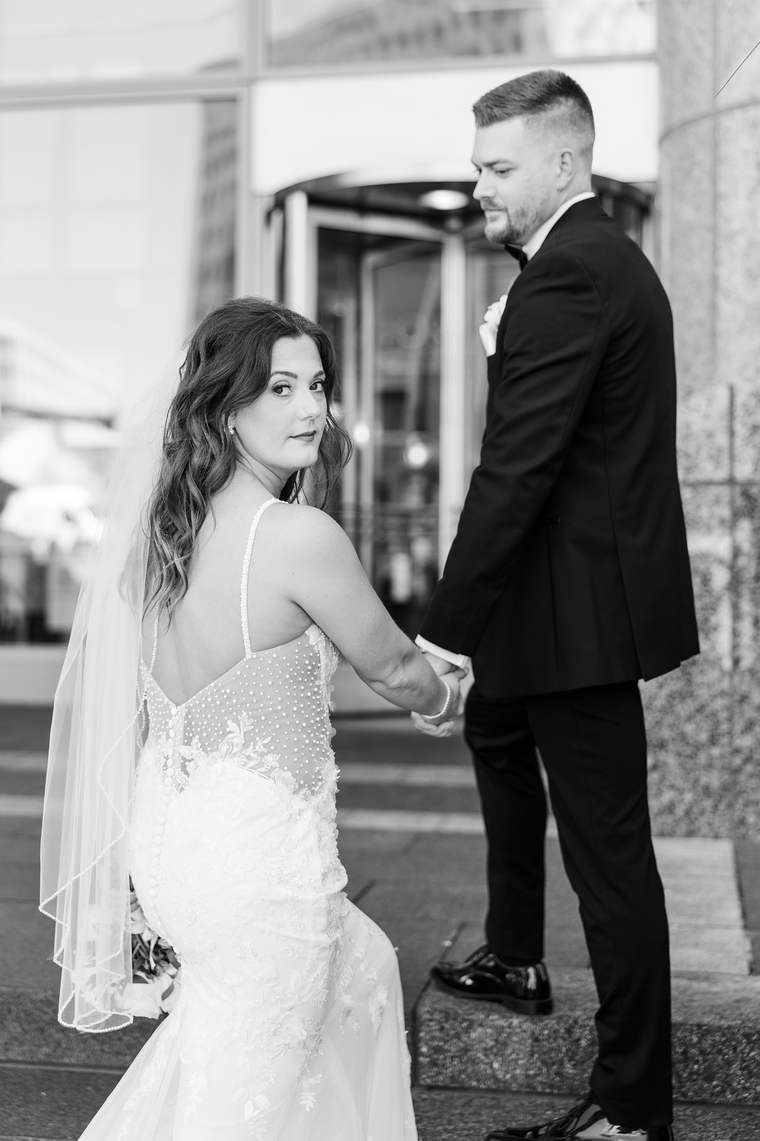 Dustin and Jenna walk up the steps of 801 Grand in downtown Des Moines while Jenna looks back intently | CB Studio