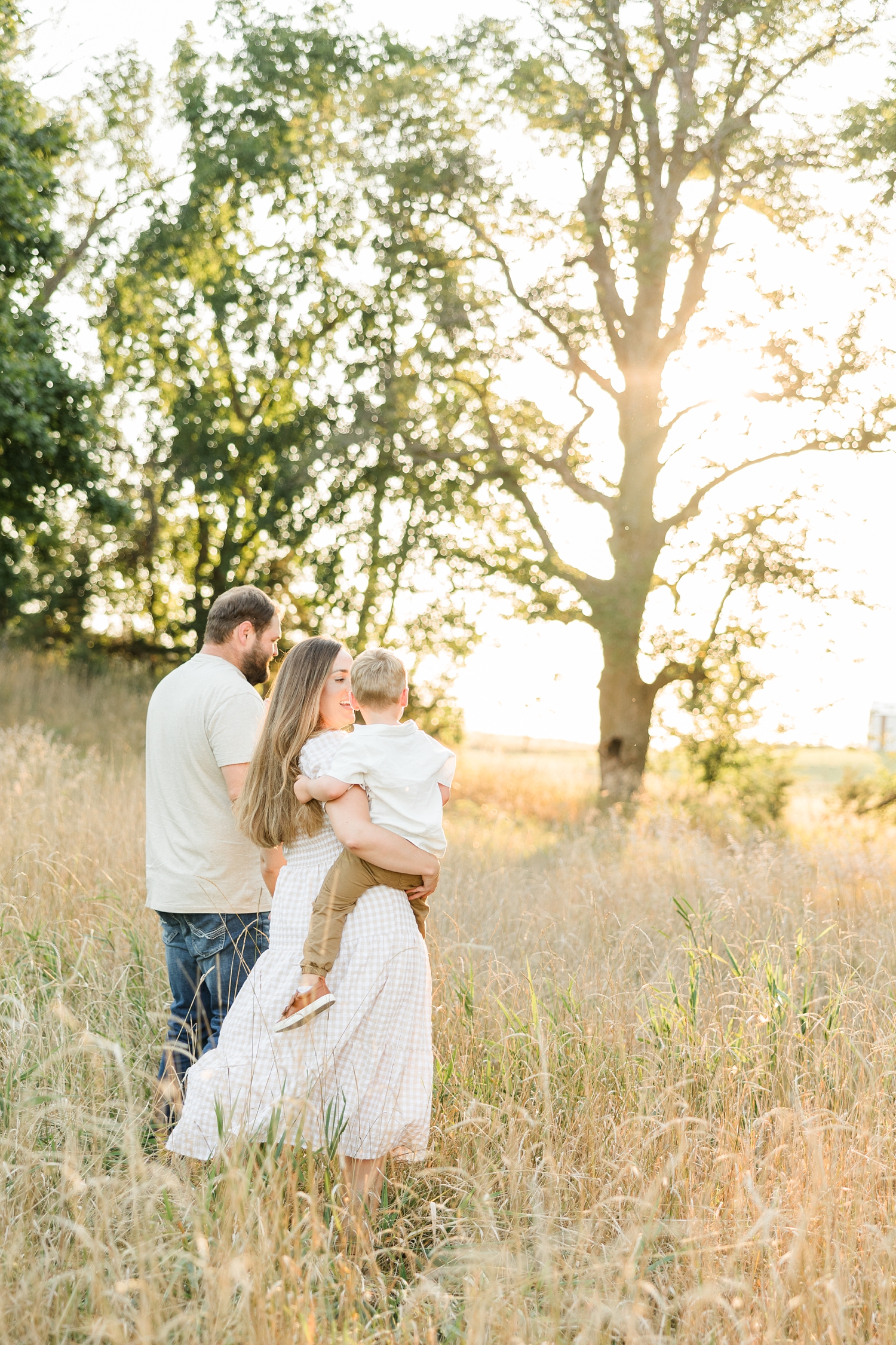 The Mathisens walk in a grassy pasture during golden hour | CB Studio