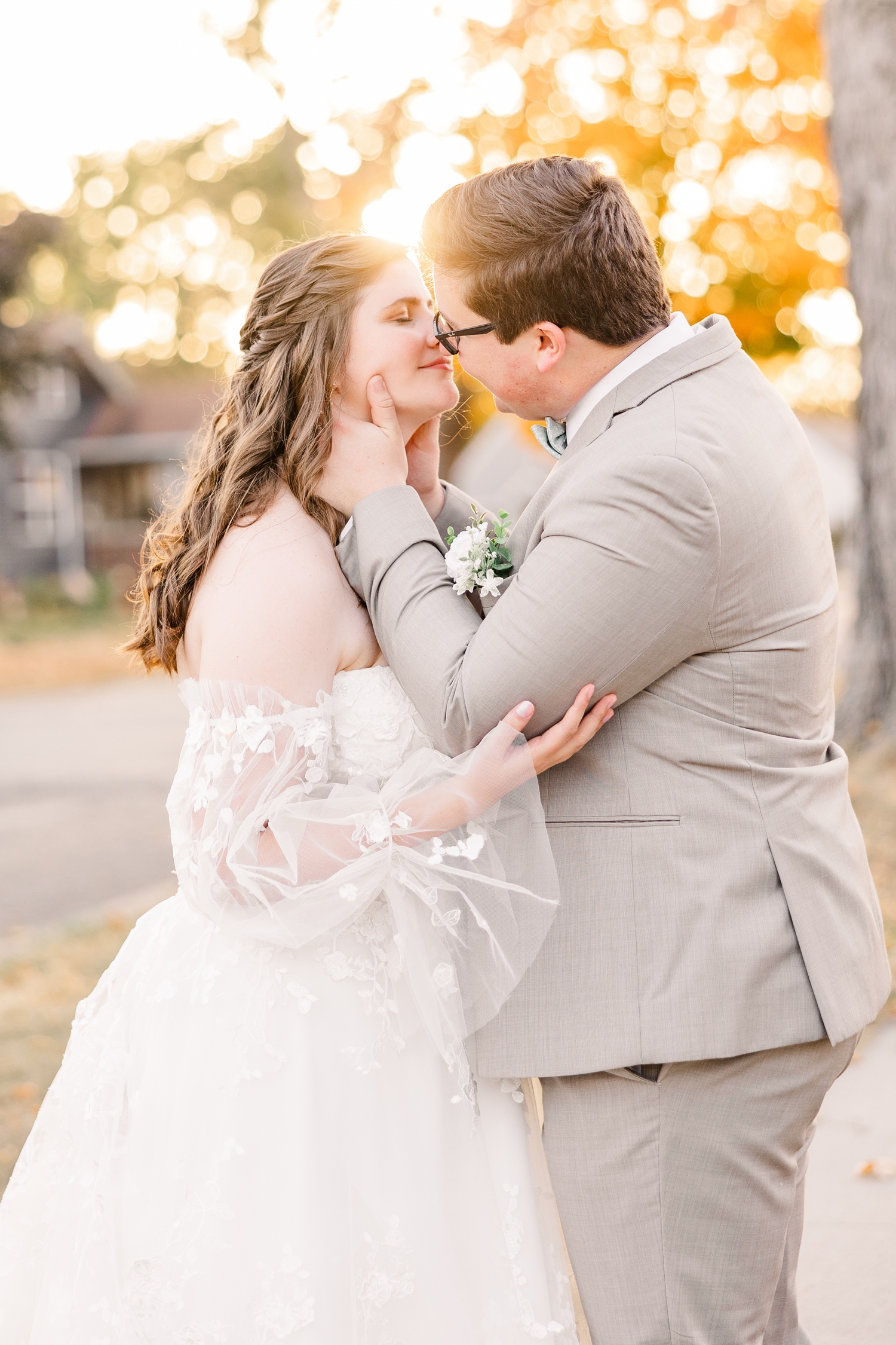 Kevin, while holding Myra's face, pulls her in slowly for a kiss with the sunset and fall foliage surrounding them in the background | CB Studio