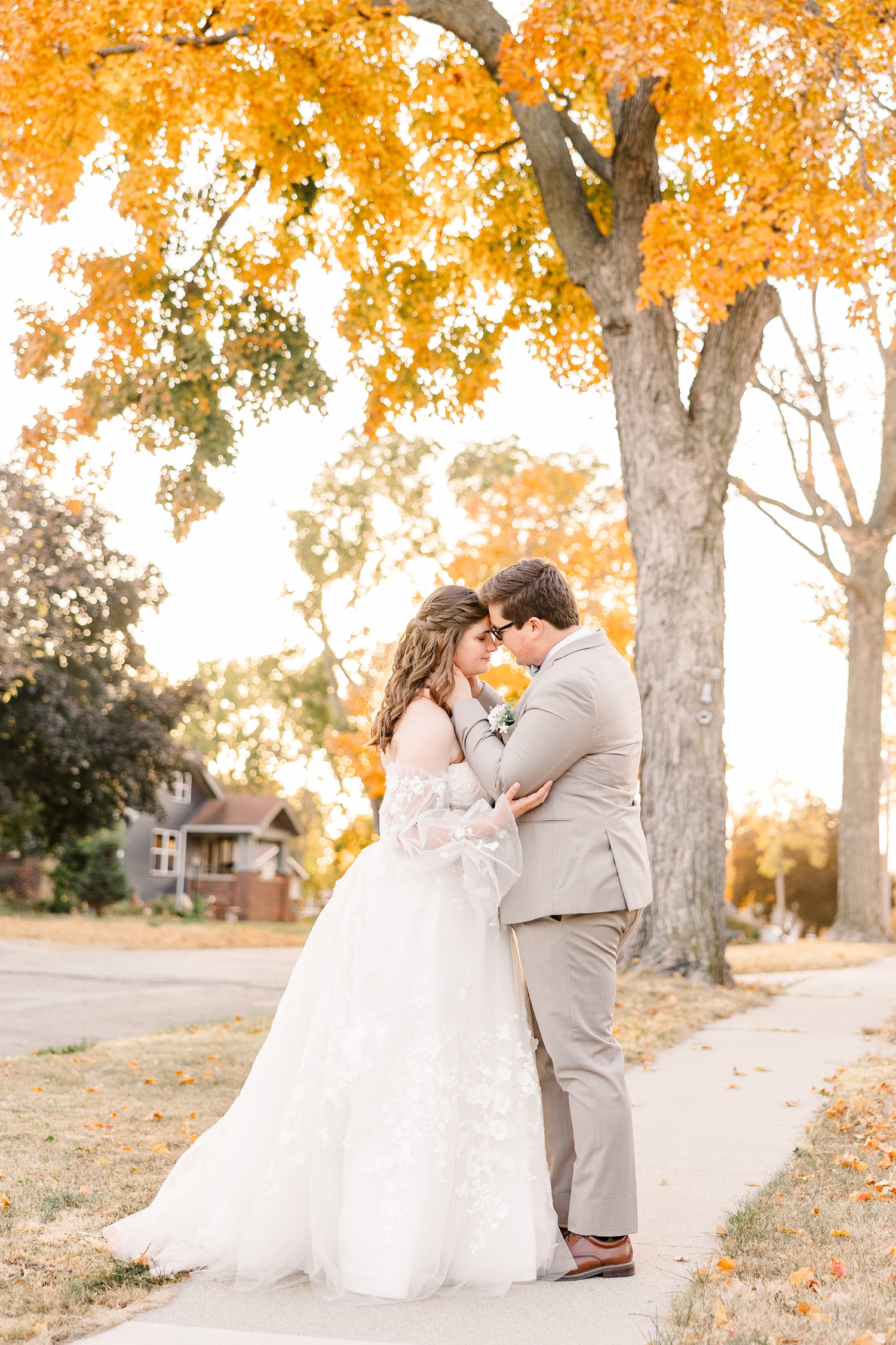 Kevin and Myra standing facing each other as they rest their foreheads together under an orange maple tree at peek fall foliage | CB Studio