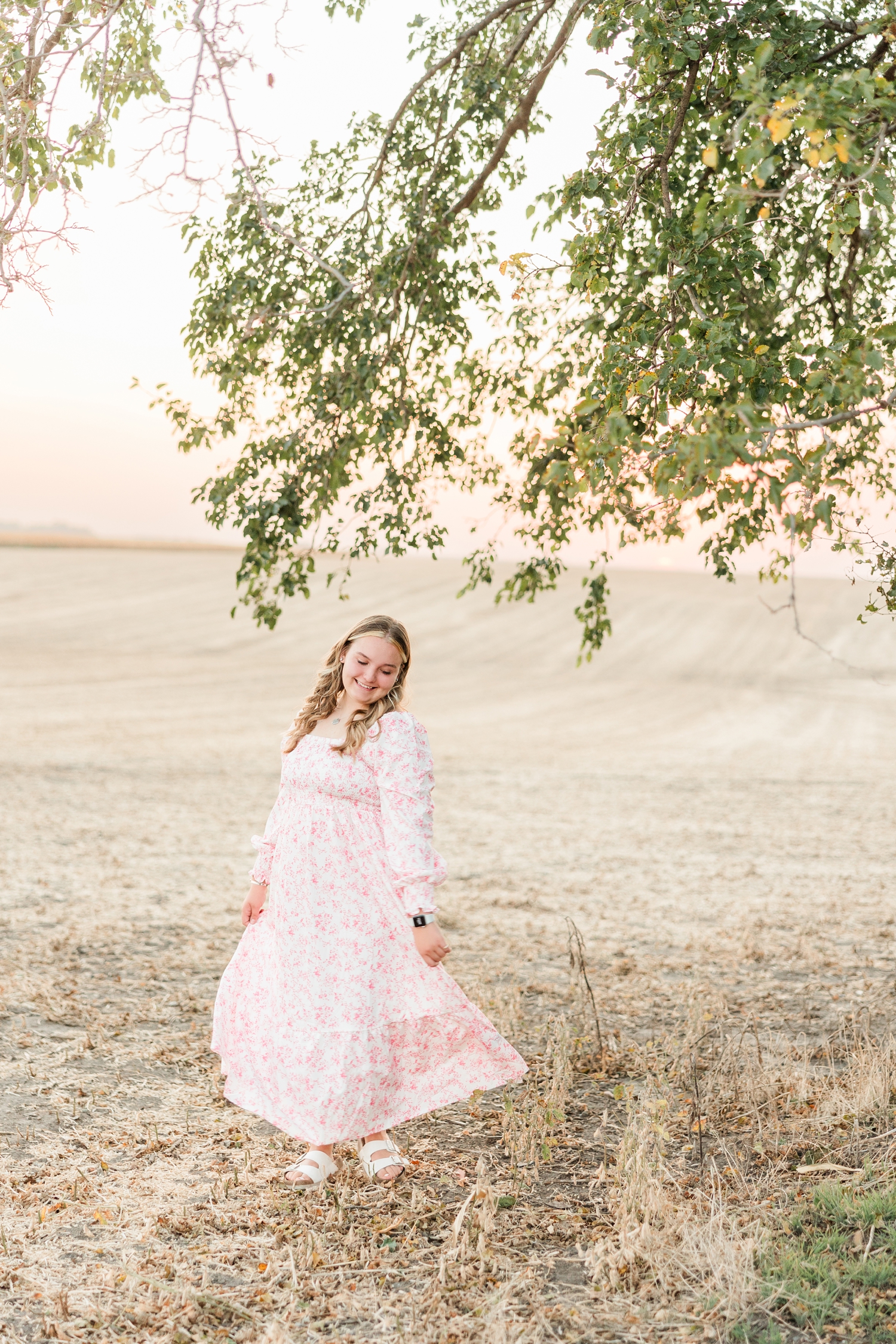 Shelby twirls her pink floral maxi dress in the middle of a bean field that had just been harvested with a pink sunset in the background | CB Studio