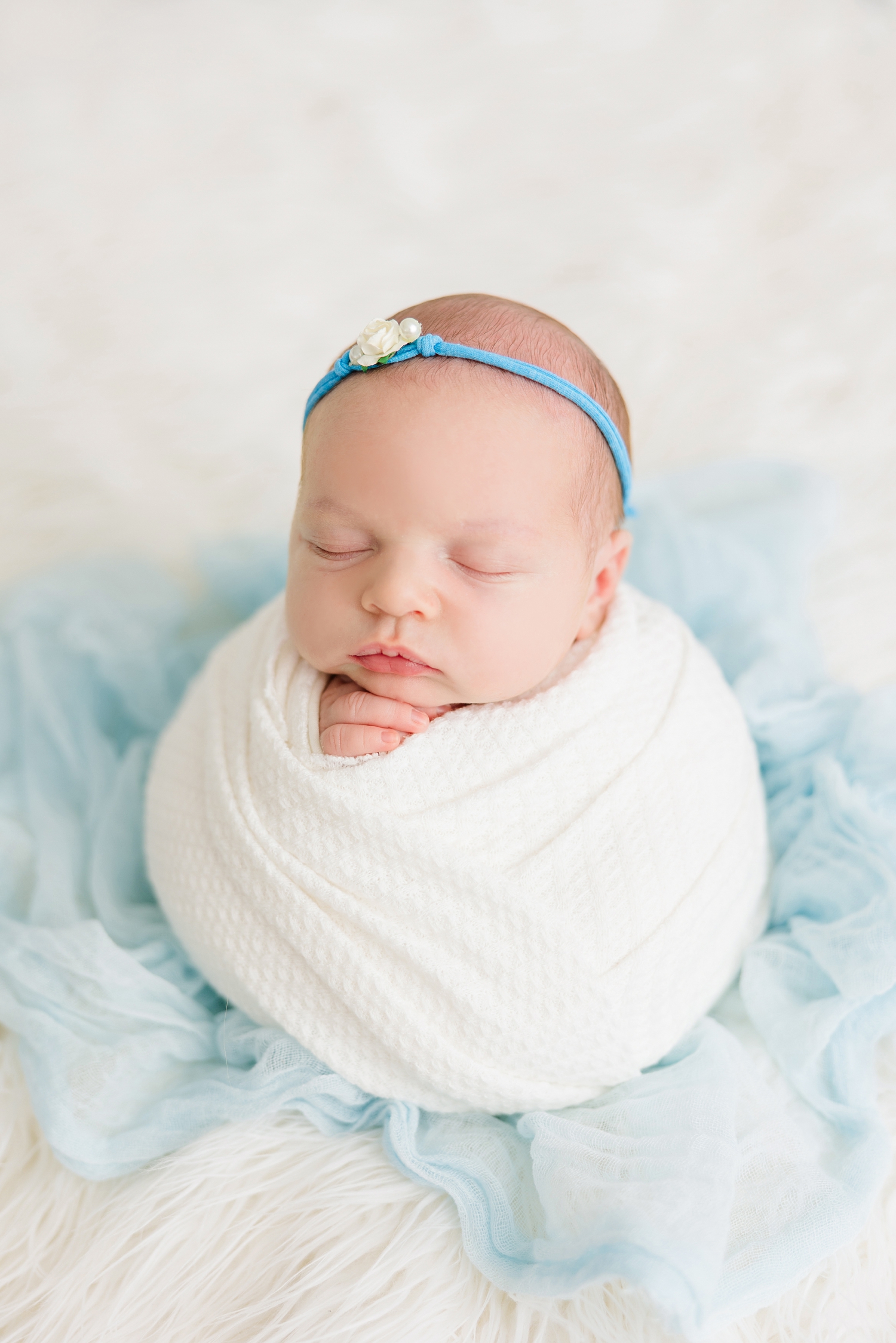 Baby Sadie wrapped in a potato sack pose in all white with little pop of light blue in her headband and layering cloth | CB Studio