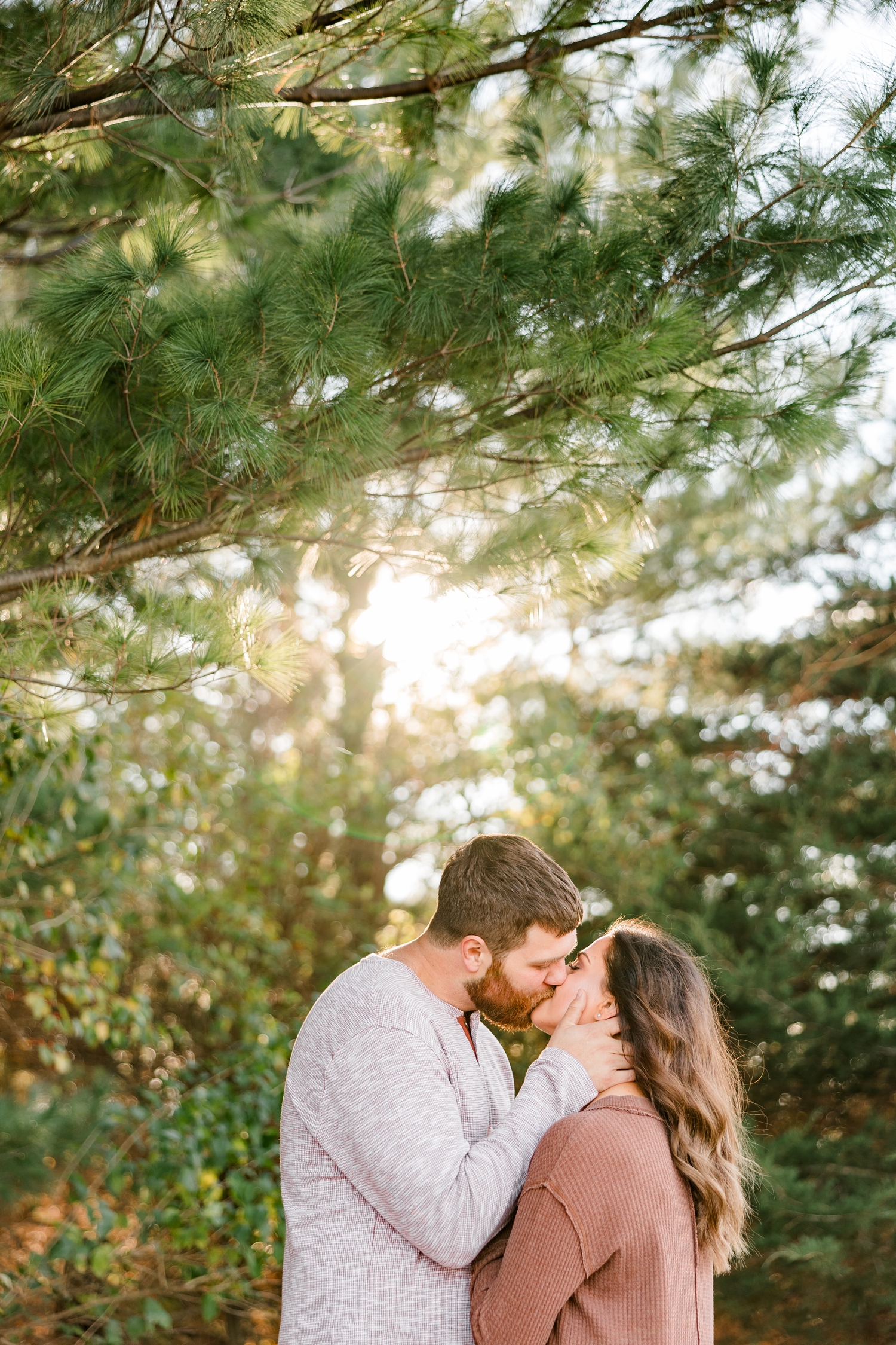 Drake gently pulls Kylie in for a kiss as they are surrounded by evergreen trees as the sun is setting | CB Studio